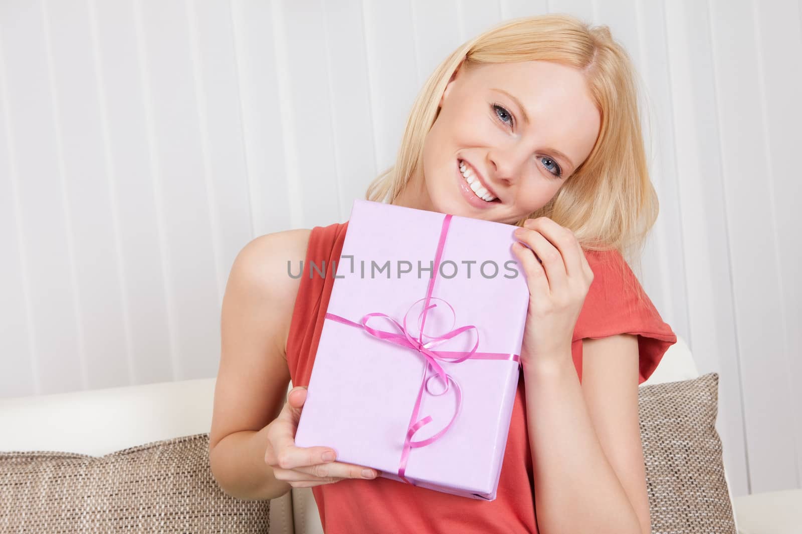 Beautiful young woman with her present on the sofa