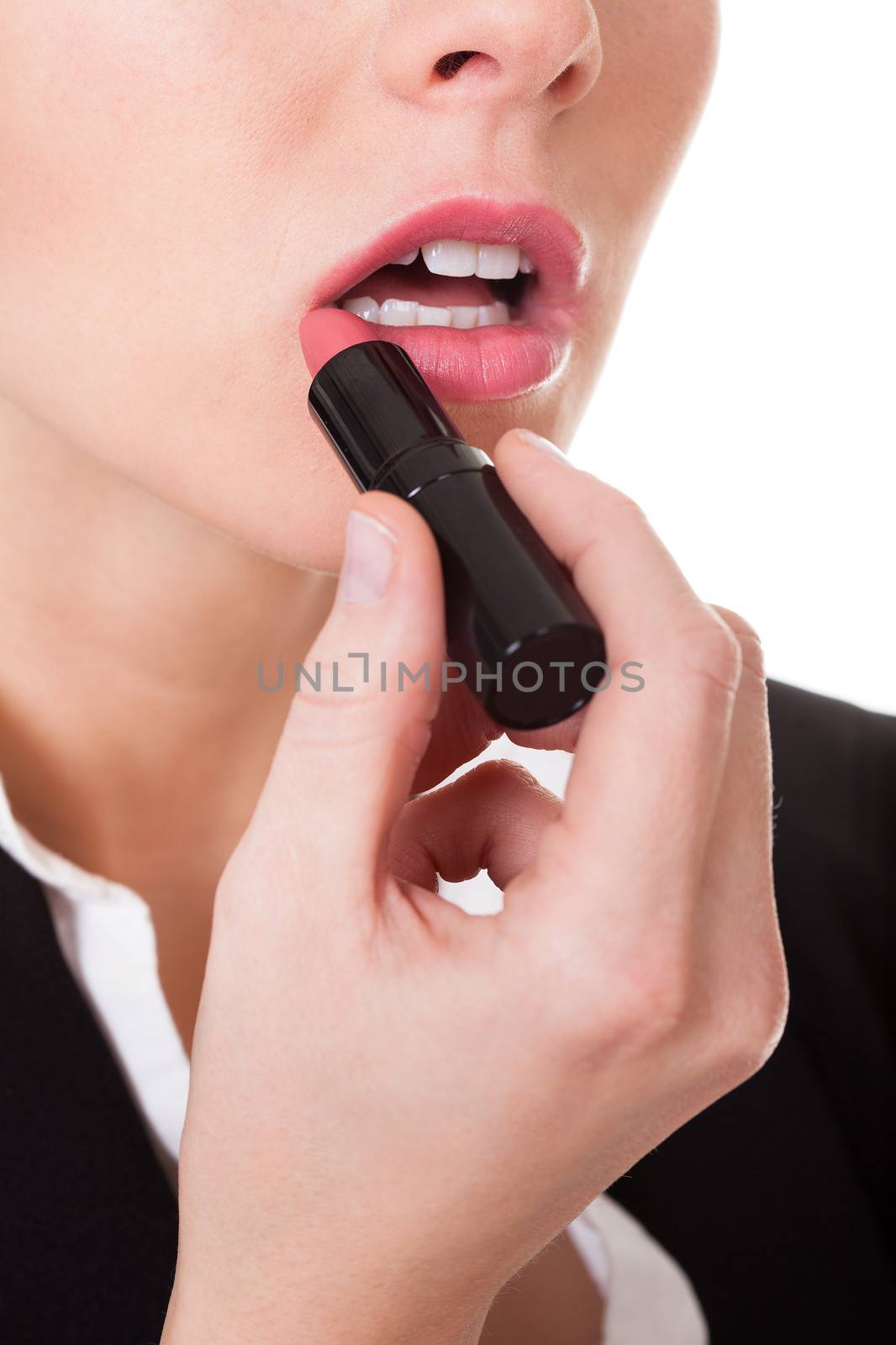Attractive businesswoman applying lipstick. Isolated on white