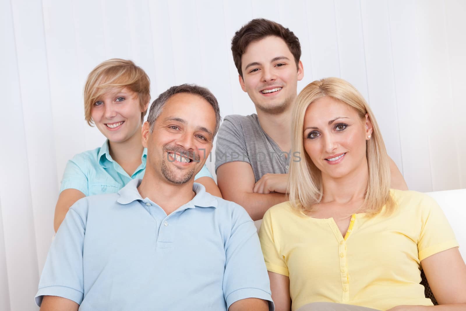 Smiling attractive young family with a teenage son and daughter posing together in group portrait