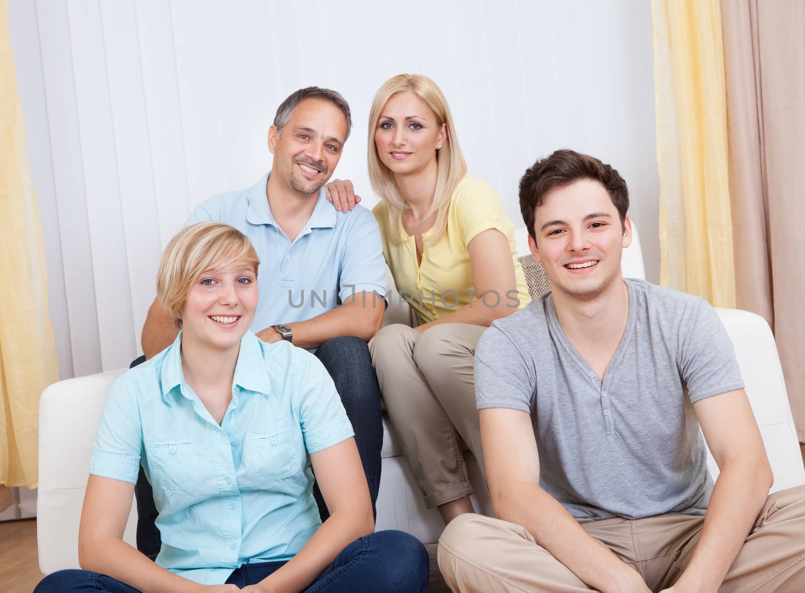 Smiling attractive young family with a teenage son and daughter posing together in group portrait
