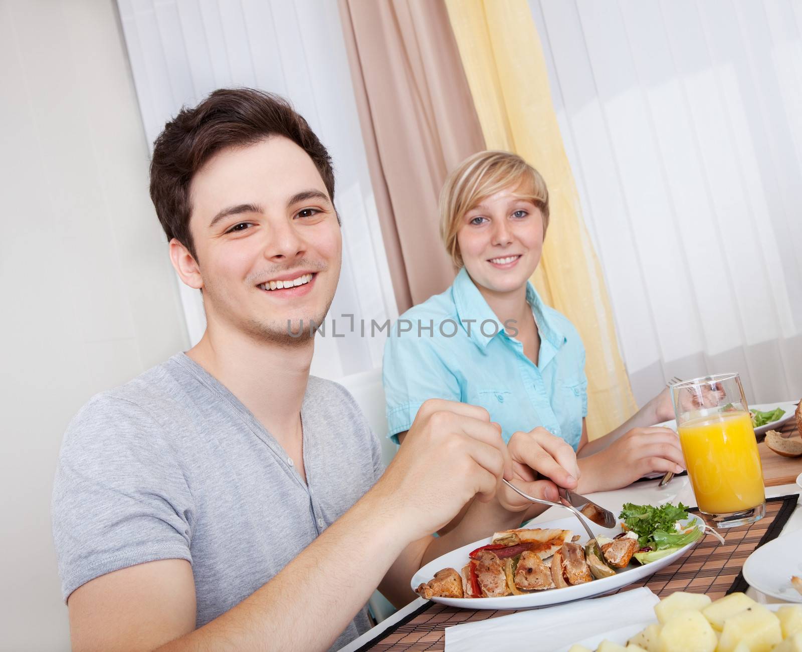 Young happy couple eating lunch at home