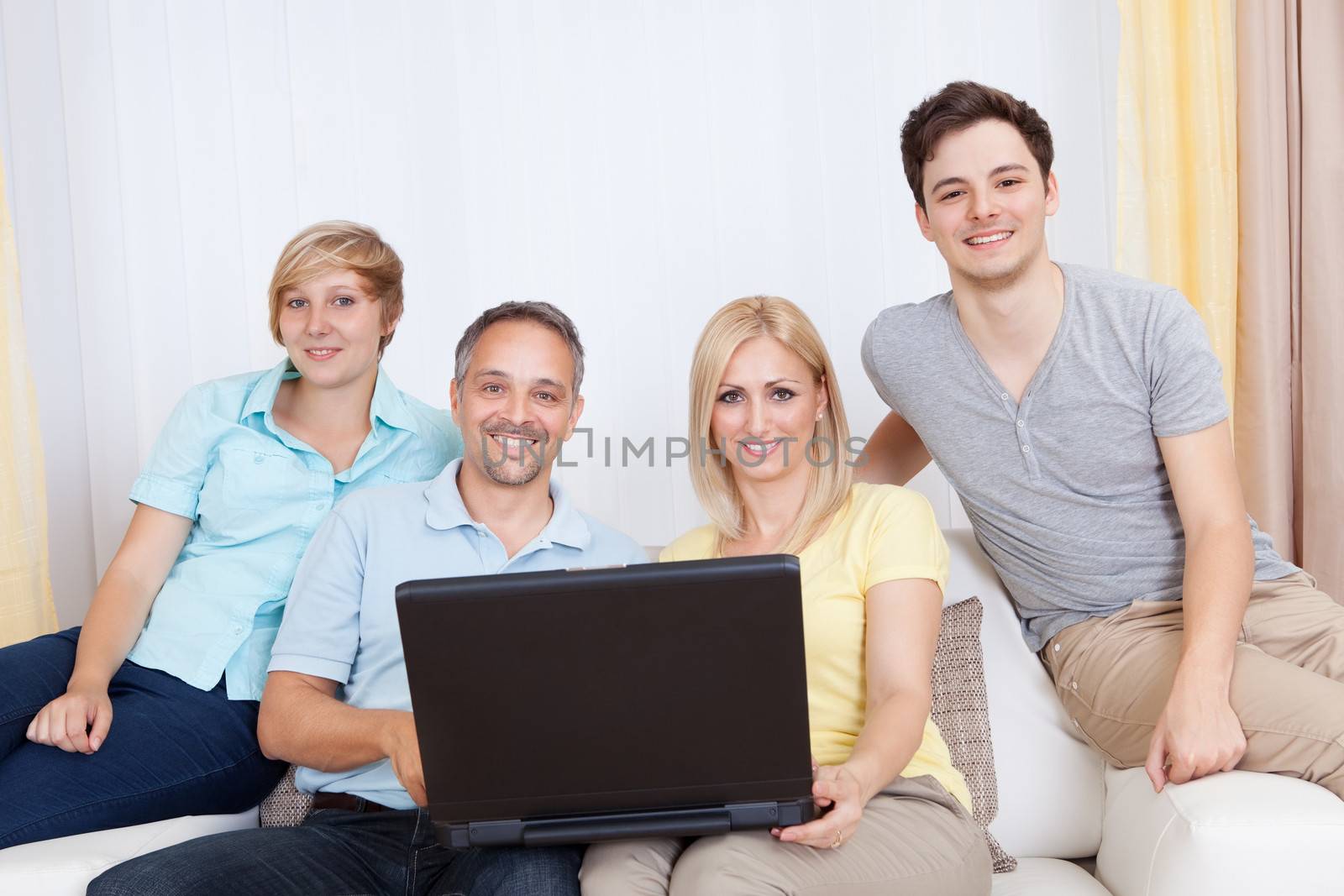 Smiling family together sitting on the couch with laptop