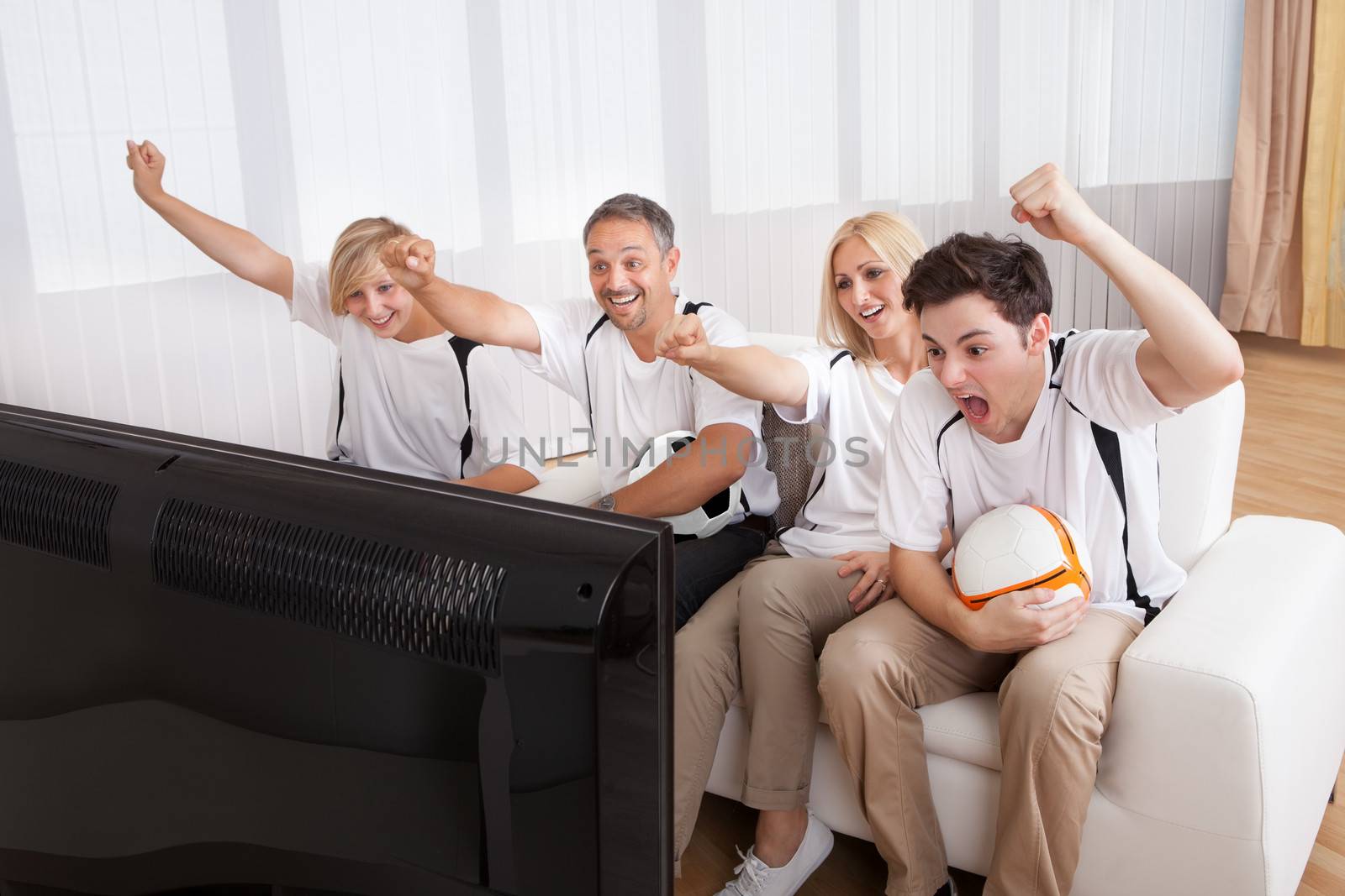 Jubilant family watching television as they cheer on their home side in a sporting competition