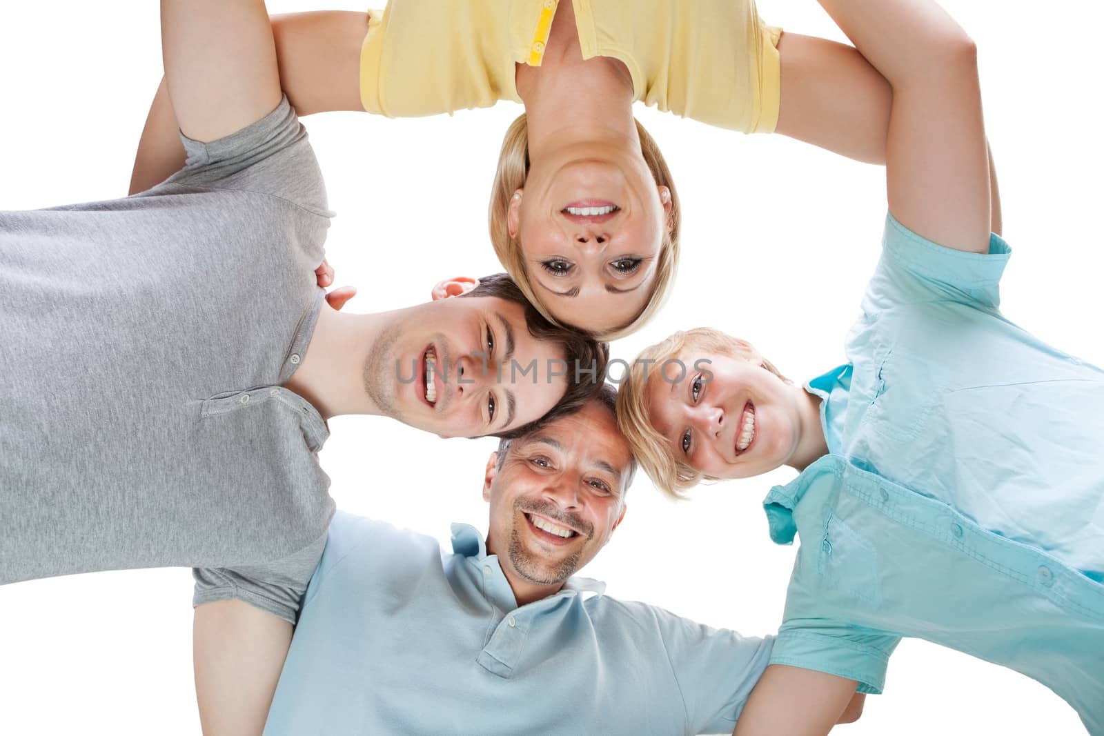 Happy family standing in a circle with their heads close together looking down at the camera with cheerful smiles