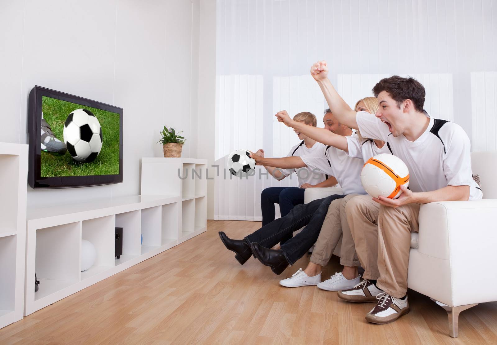 Jubilant family watching television as they cheer on their home side in a sporting competition