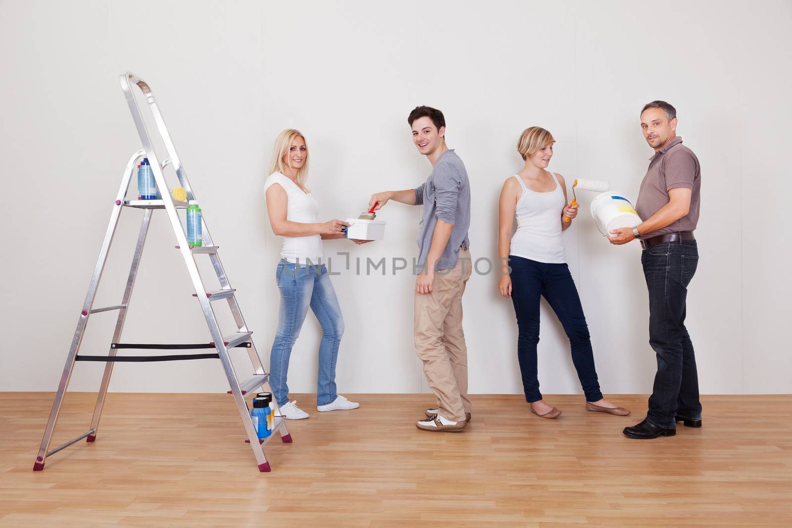 Family teamwork during home maintenance as the children repair the surface of the wall for their parents to paint