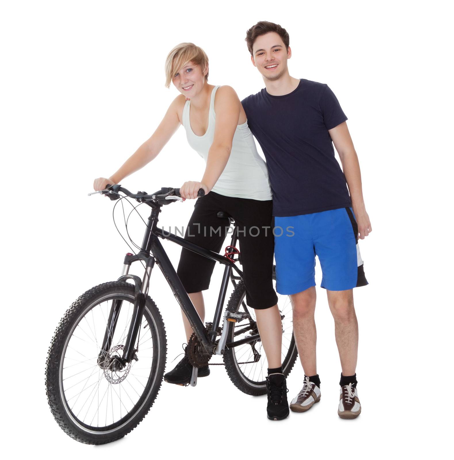 Fit healthy young couple who enjoy an active outdoor lifestyle standing with  bicycle