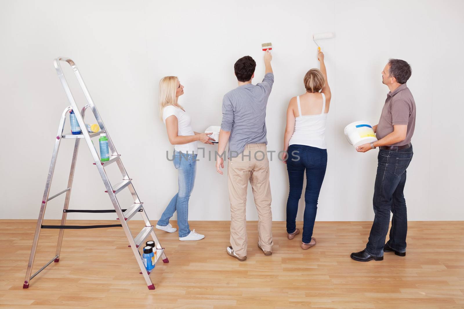 Family teamwork during home maintenance as the children repair the surface of the wall for their parents to paint