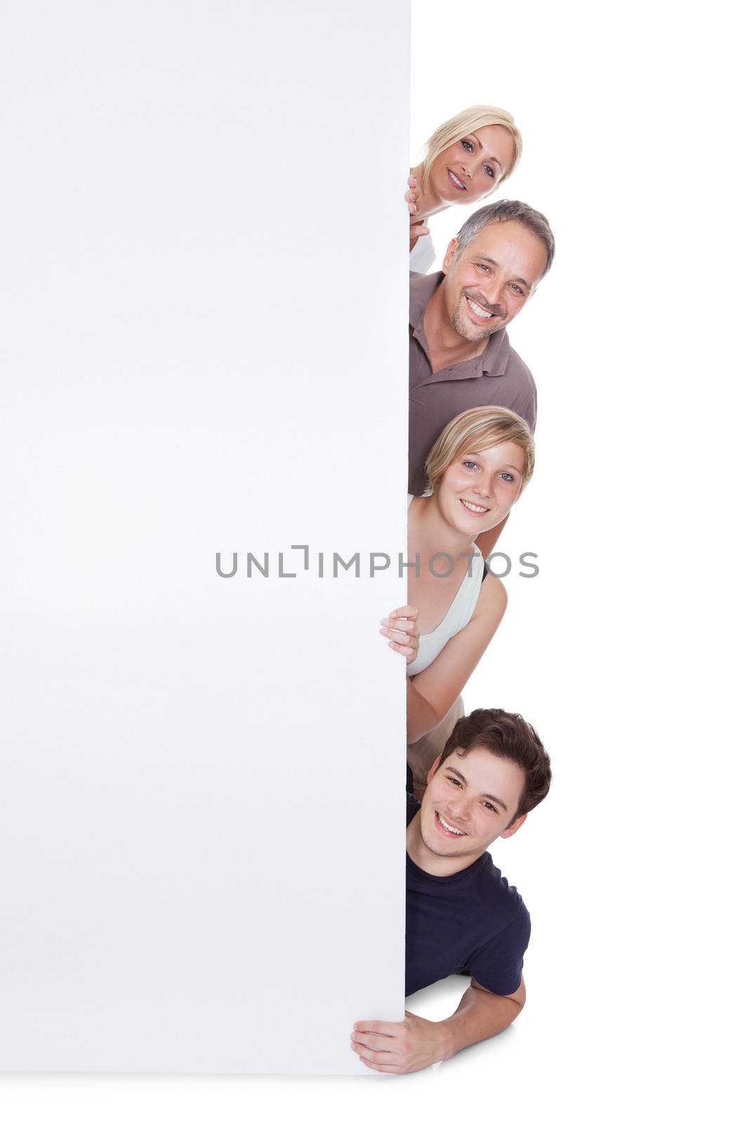 Happy family with two teenage children holding up a blank placard or sign with copyspace for your advertising of announcement