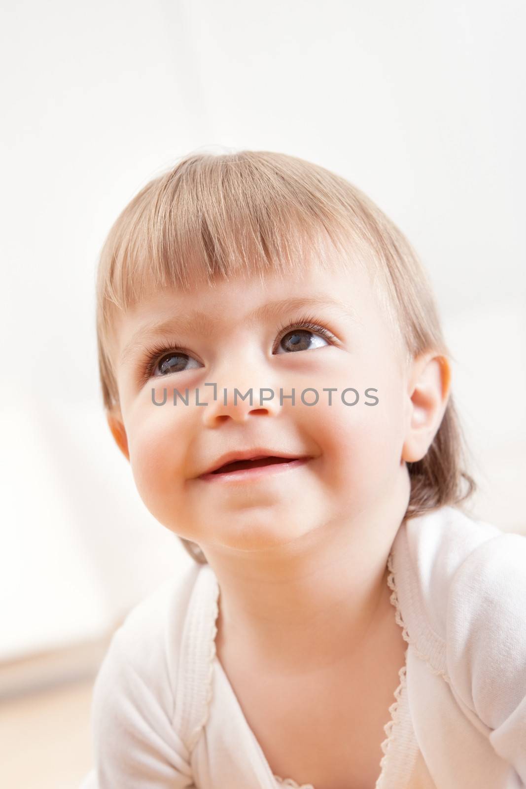 Low angle portrait of a cute innocent young baby smiling and looking up with love