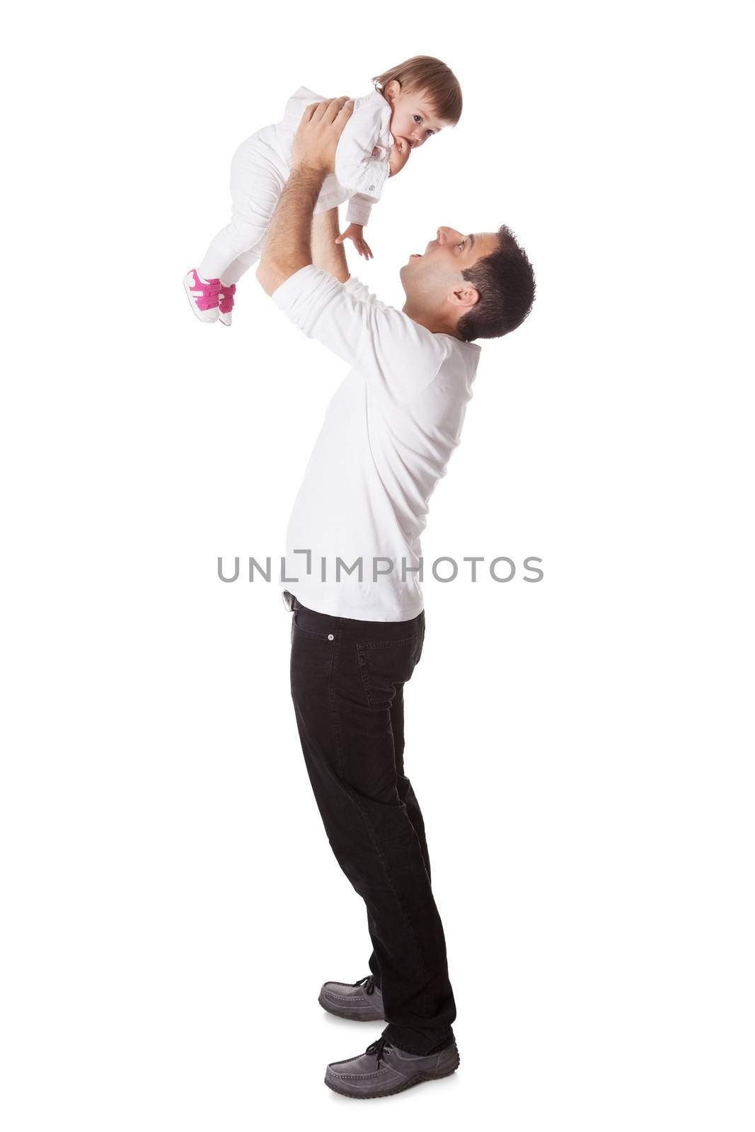 Young father playing with his small baby daughter holding her aloft with his arms extended above his head