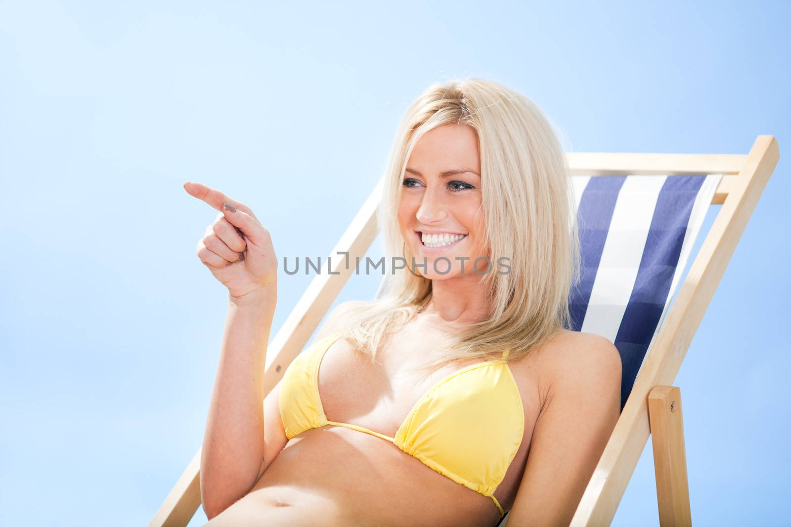 Beautiful young woman in bikini lying on a deckchair at the beach