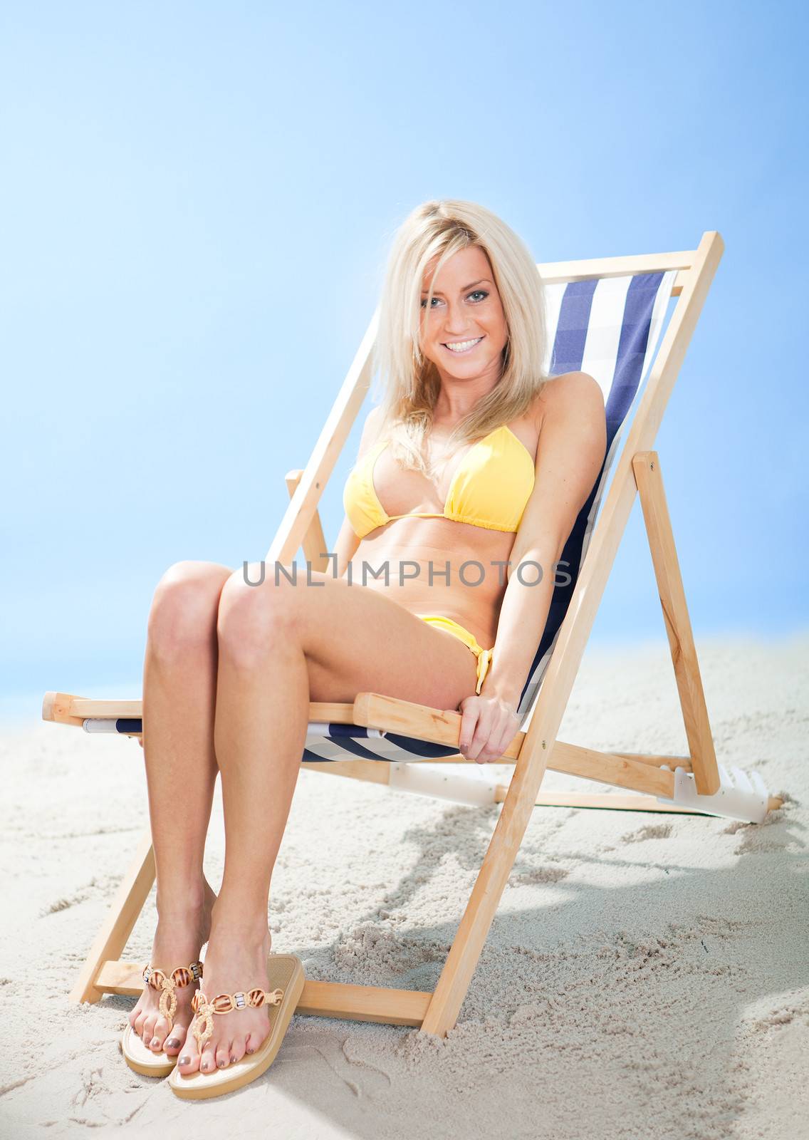 Beautiful young woman in bikini lying on a deckchair at the beach