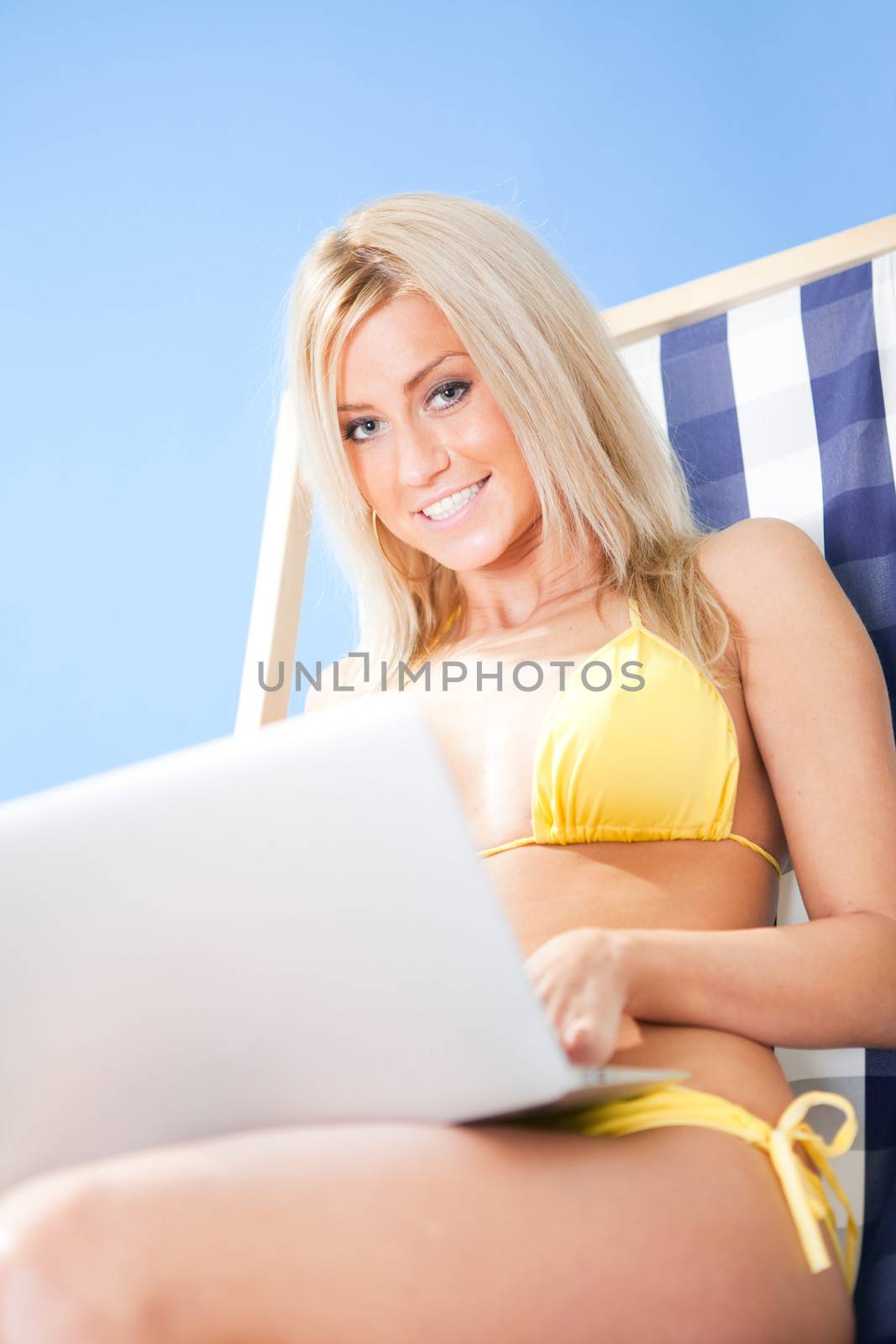 Young woman in bikini using laptop by AndreyPopov