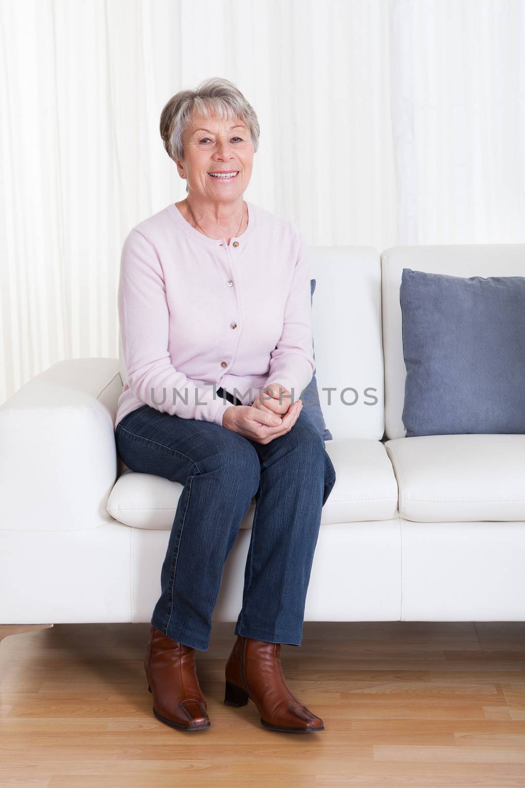 Senior Woman Sitting On The Couch by AndreyPopov