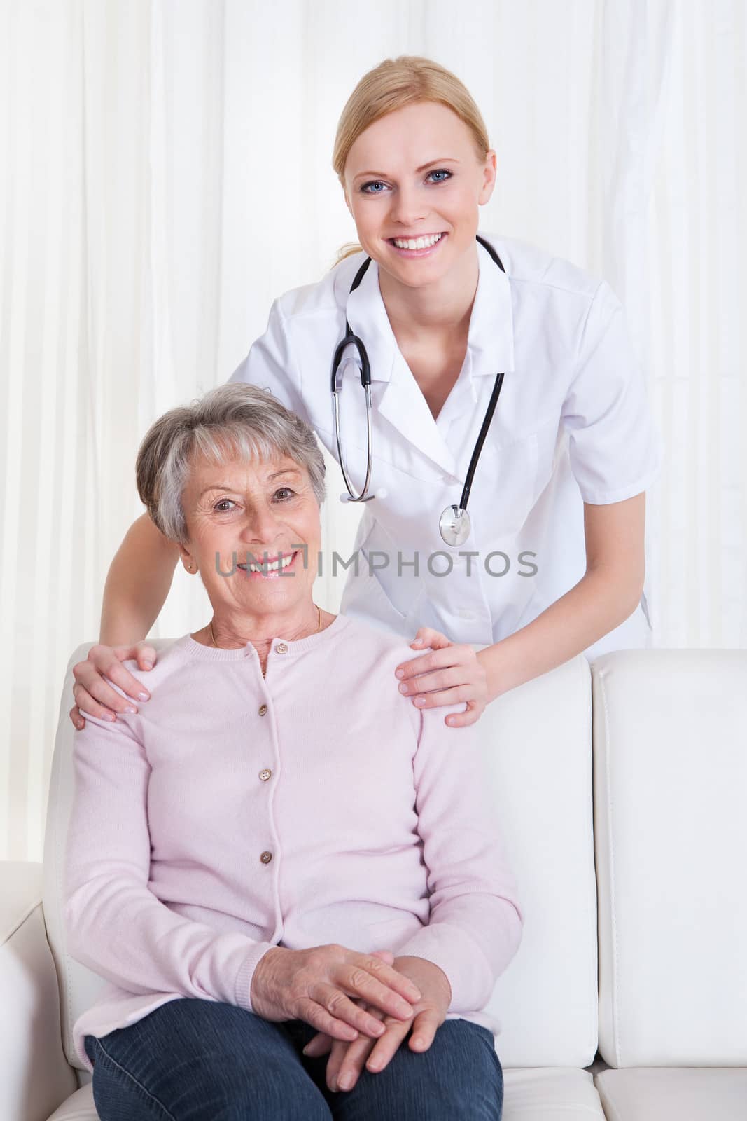 Portrait Of Young Doctor And Senior Patient Sitting On Couch