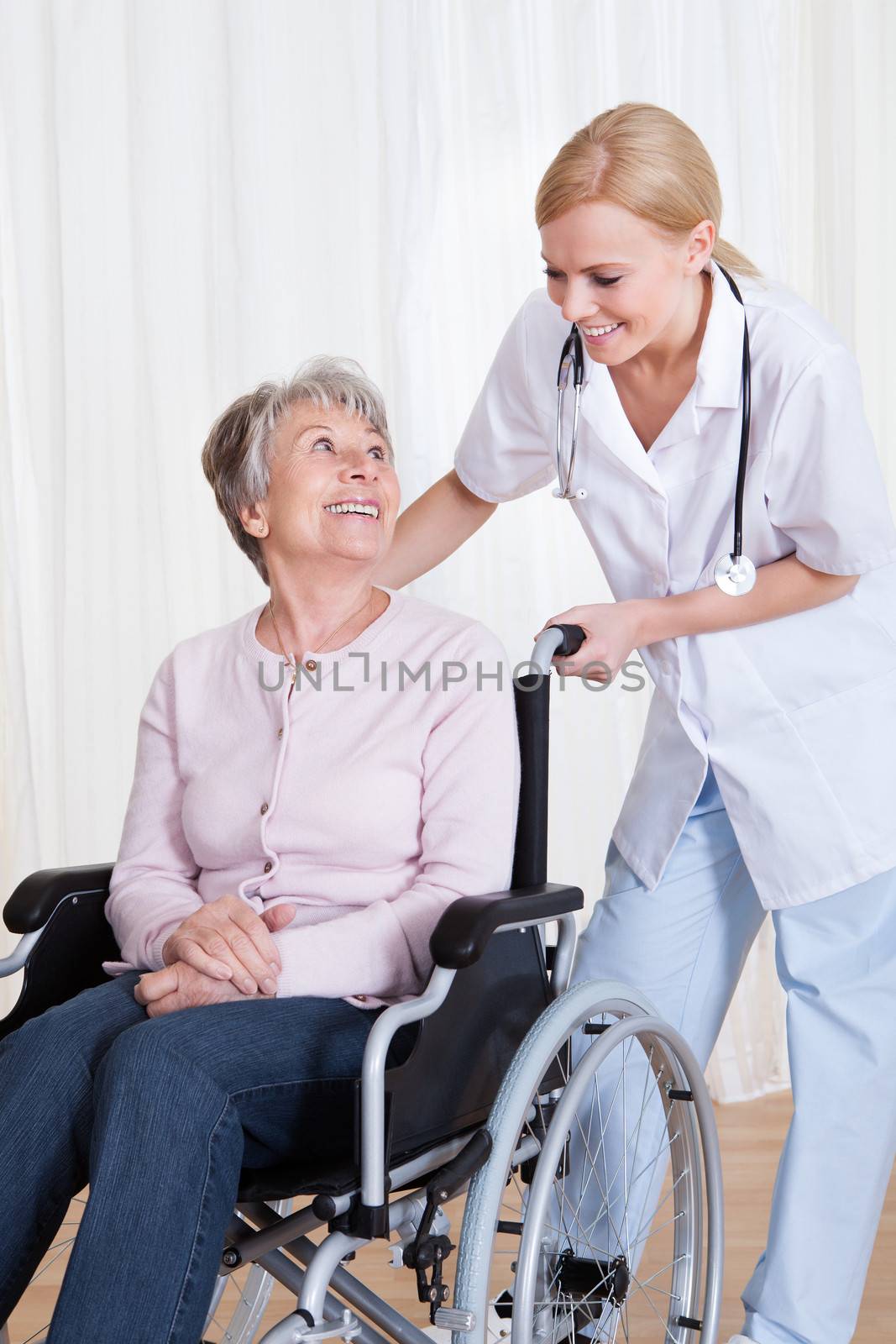 Caring Doctor Helping Handicapped Senior Patient Indoors