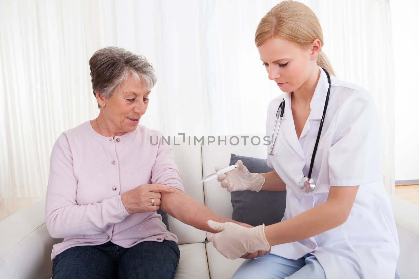 Young Female Doctor Injecting Vaccine To Senior Woman; Indoor
