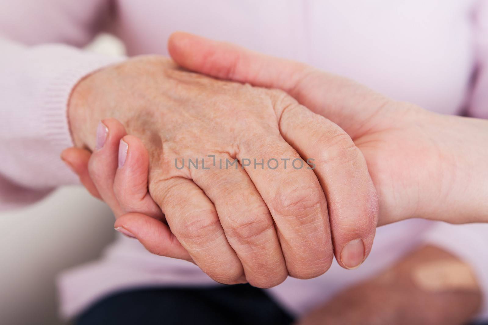 Young Woman Holding Senior Woman's Hand by AndreyPopov