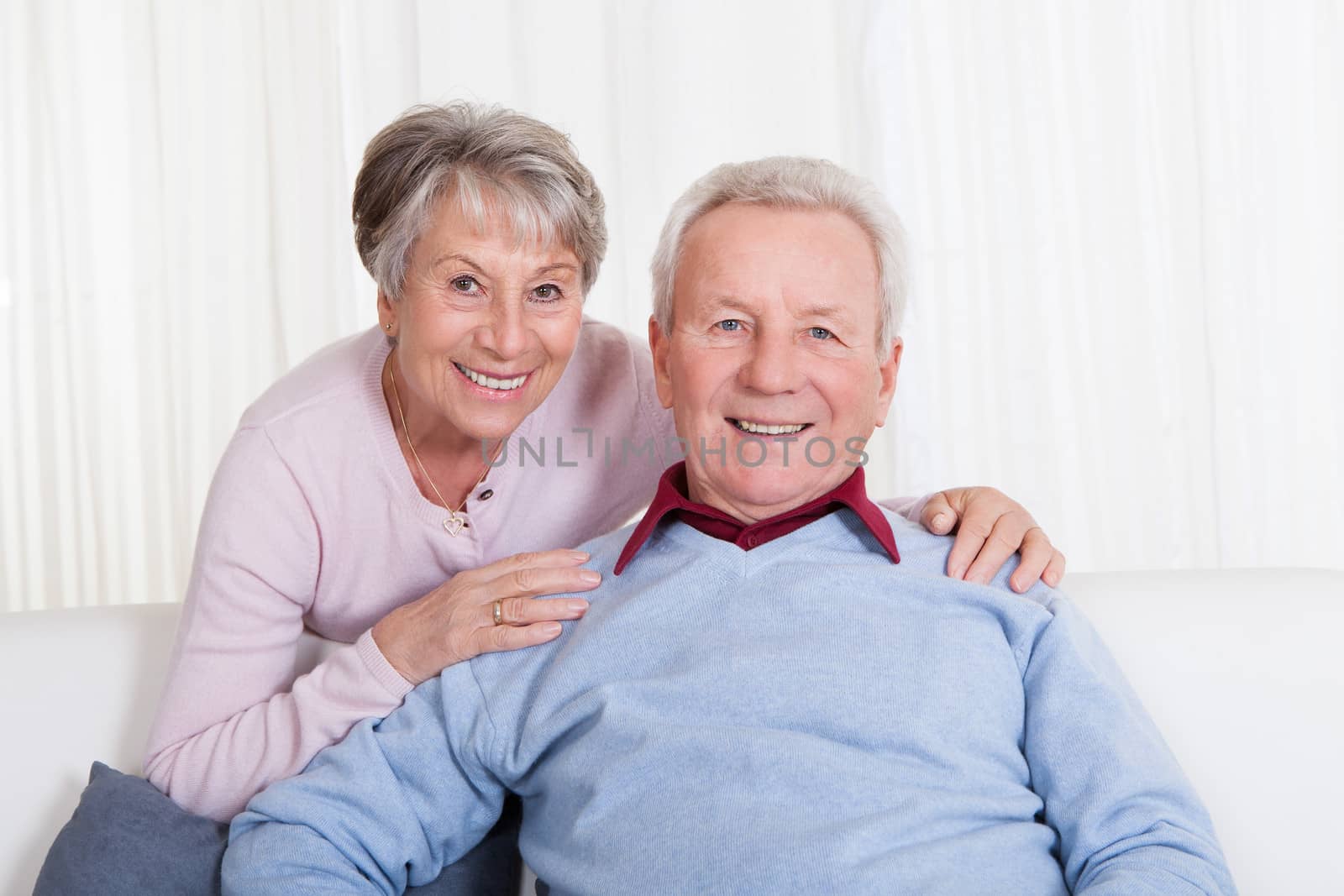 Portrait Of Happy Senior Couple Sitting On Couch