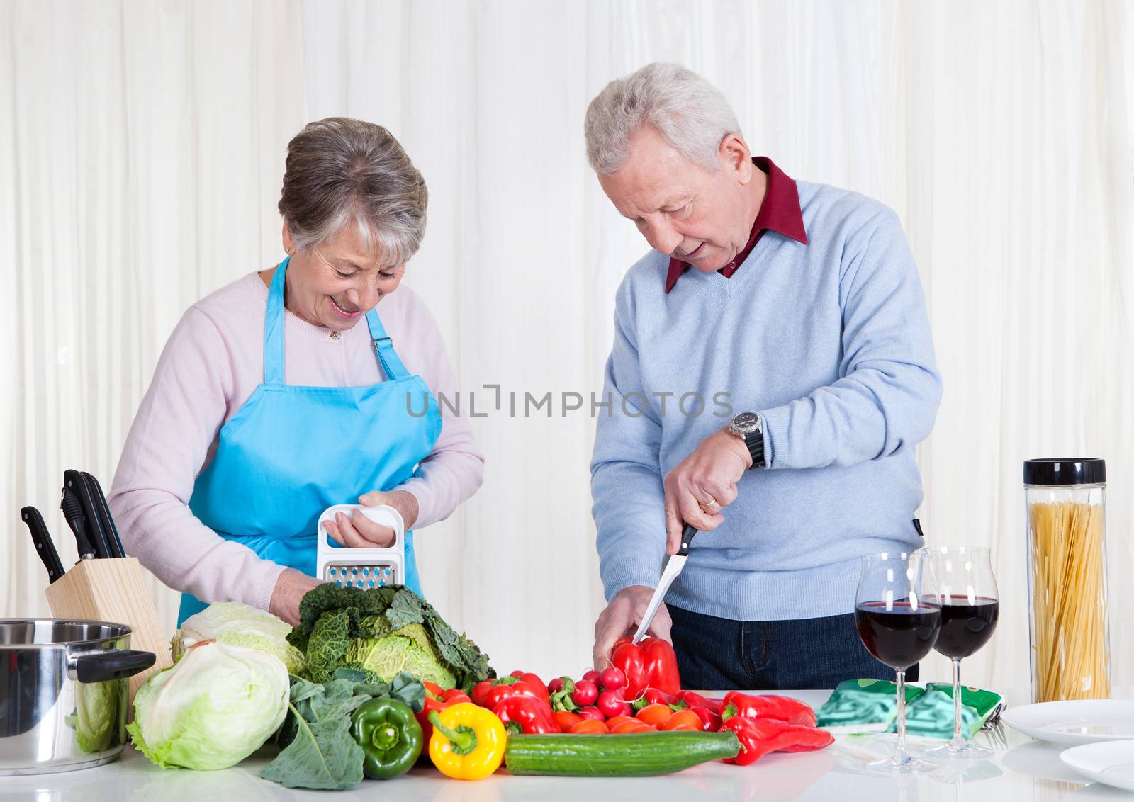 Happy Senior Couple Cutting Vegetables In Kitchen