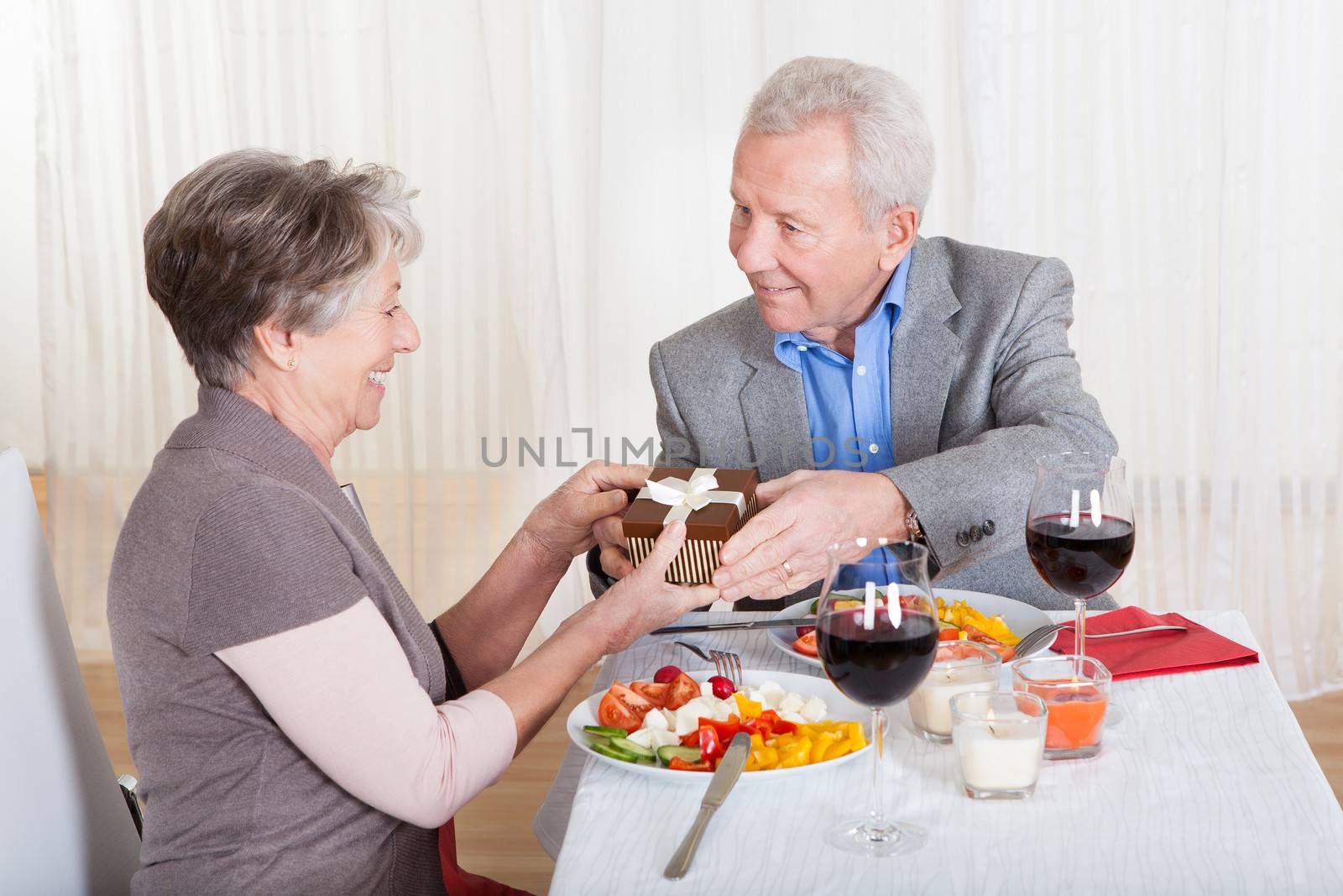 Senior Man Giving Gift To Senior Woman In Restaurant