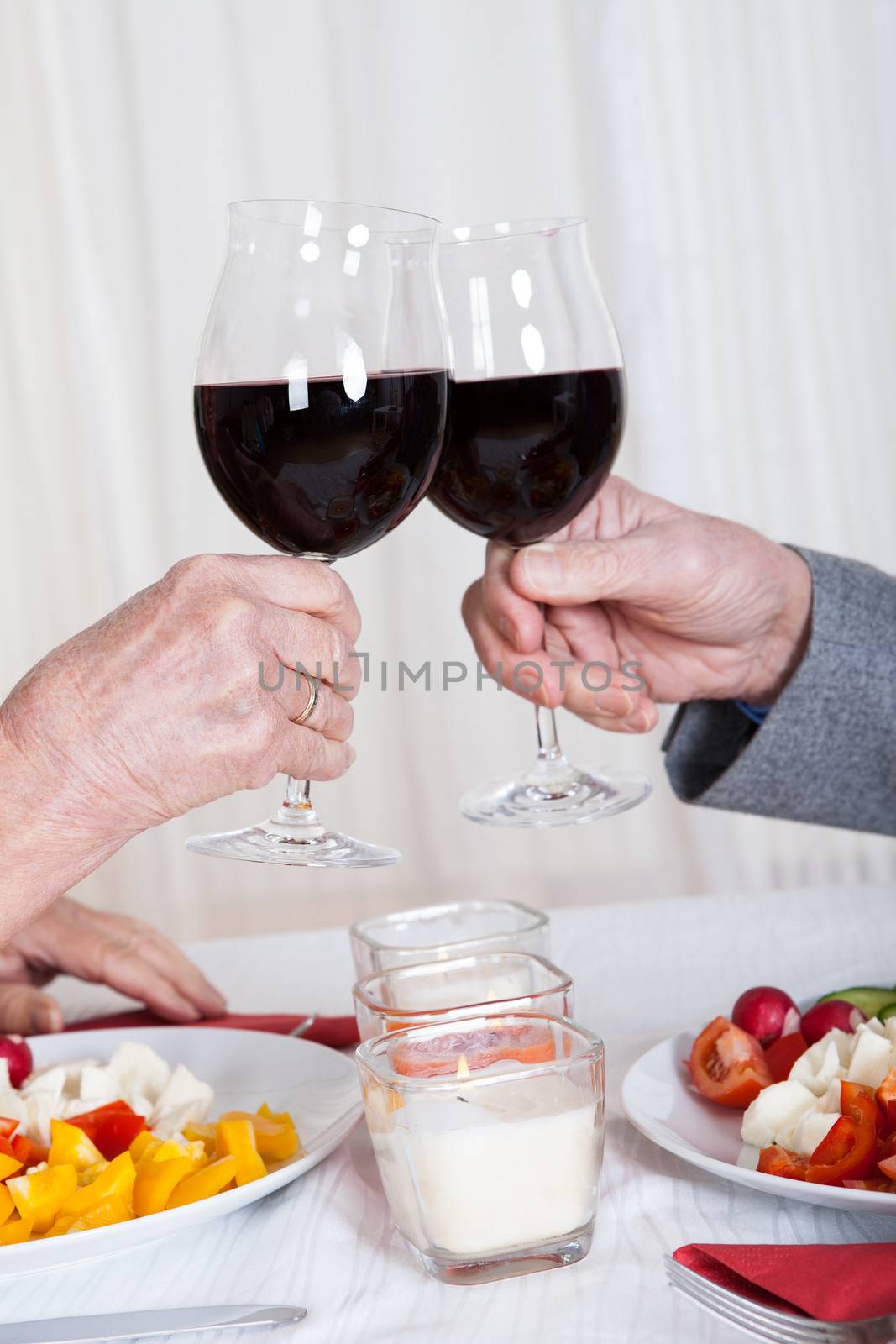 Close-up Of Hands Toasting Wine Glasses by AndreyPopov