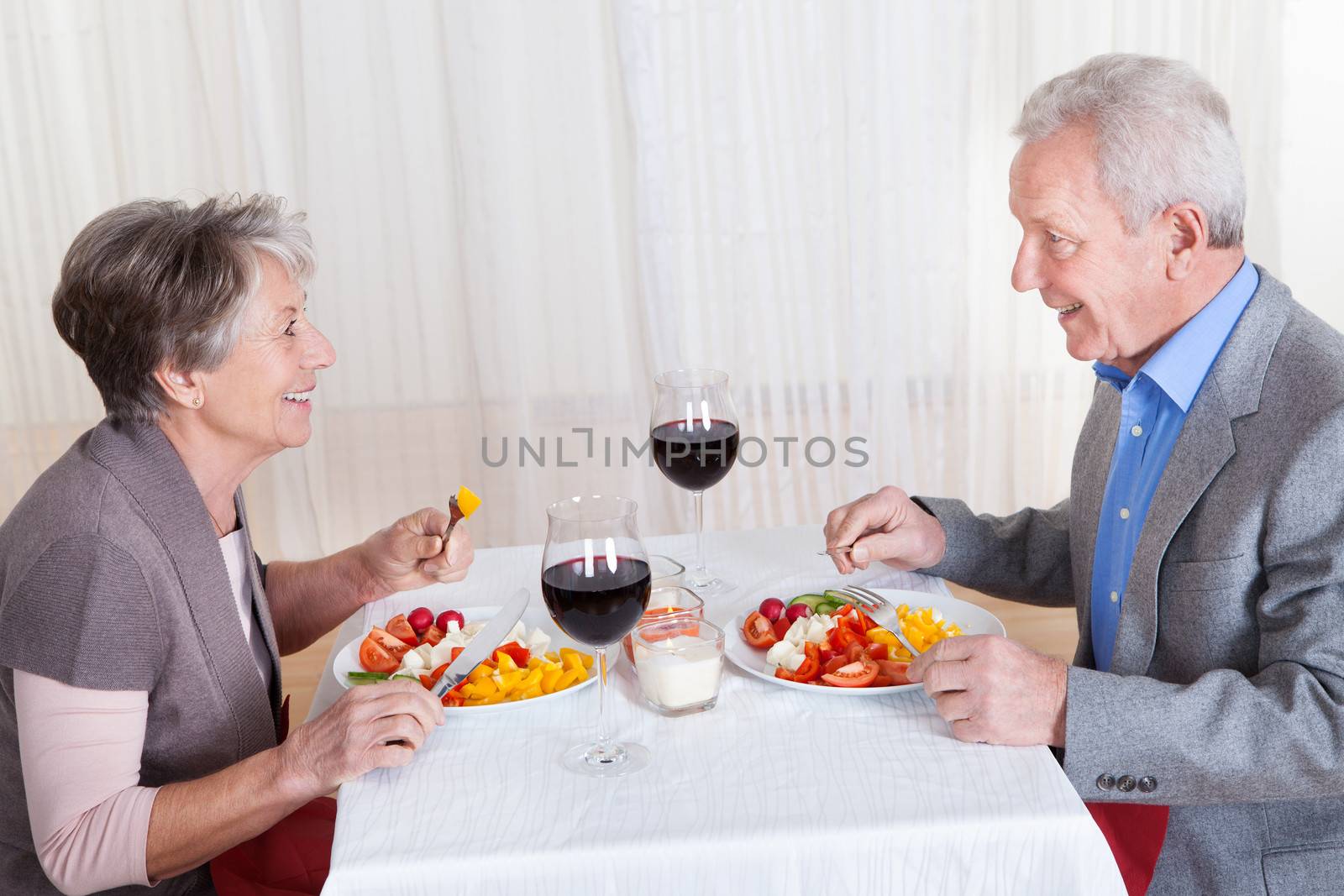 Portrait Of Senior Couple With Wine Glasses Sitting At A Restaurant