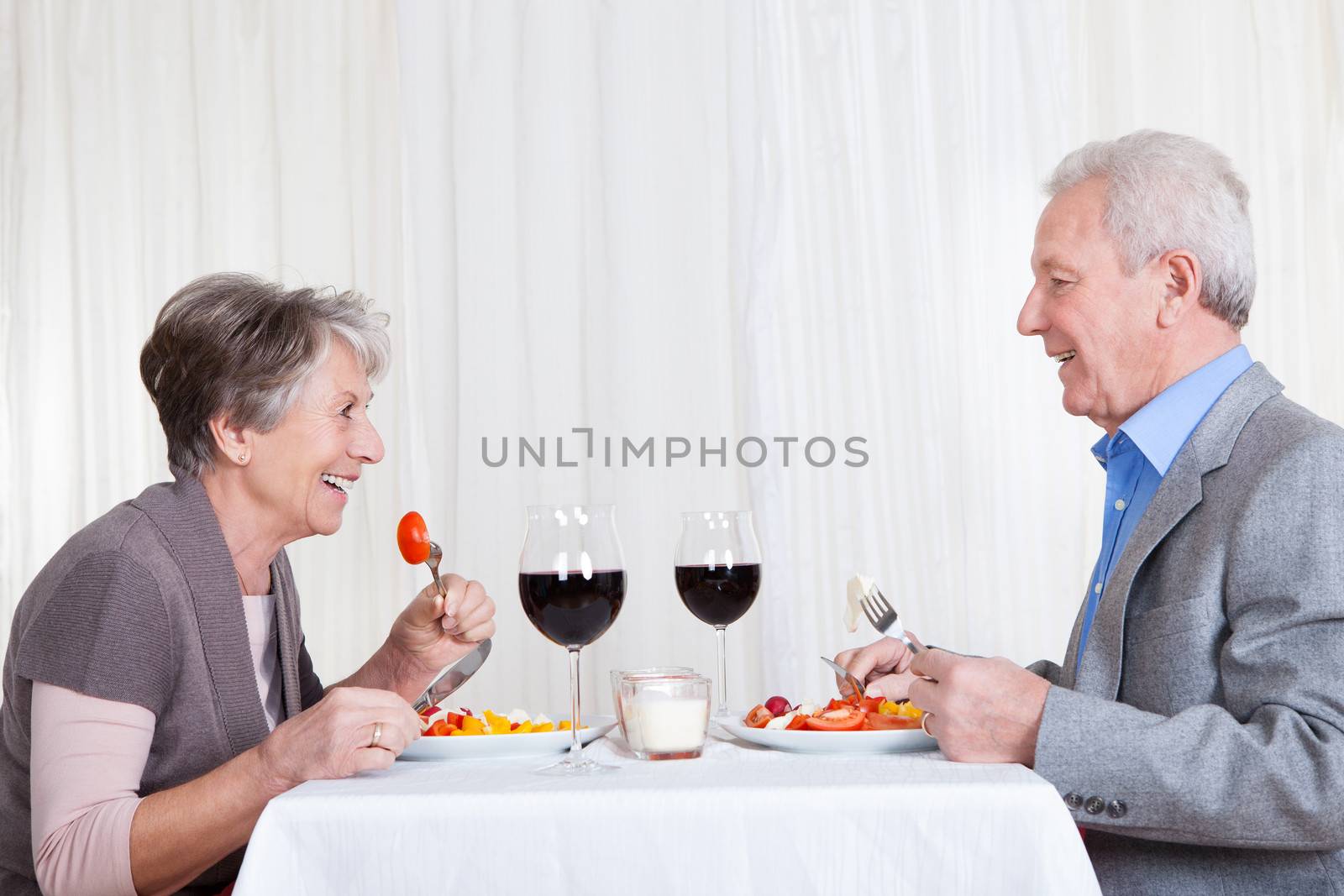 Portrait Of Senior Couple With Wine Glasses Sitting At A Restaurant