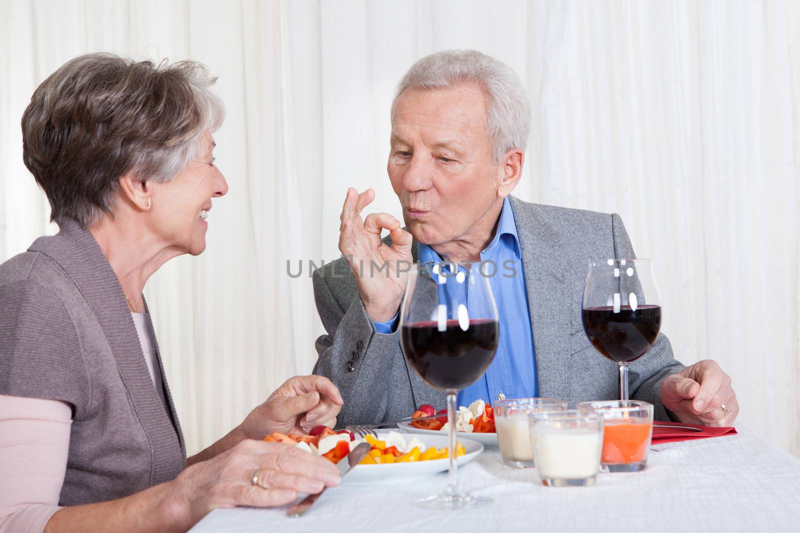 Portrait Of Senior Couple With Wine Glasses Sitting At A Restaurant