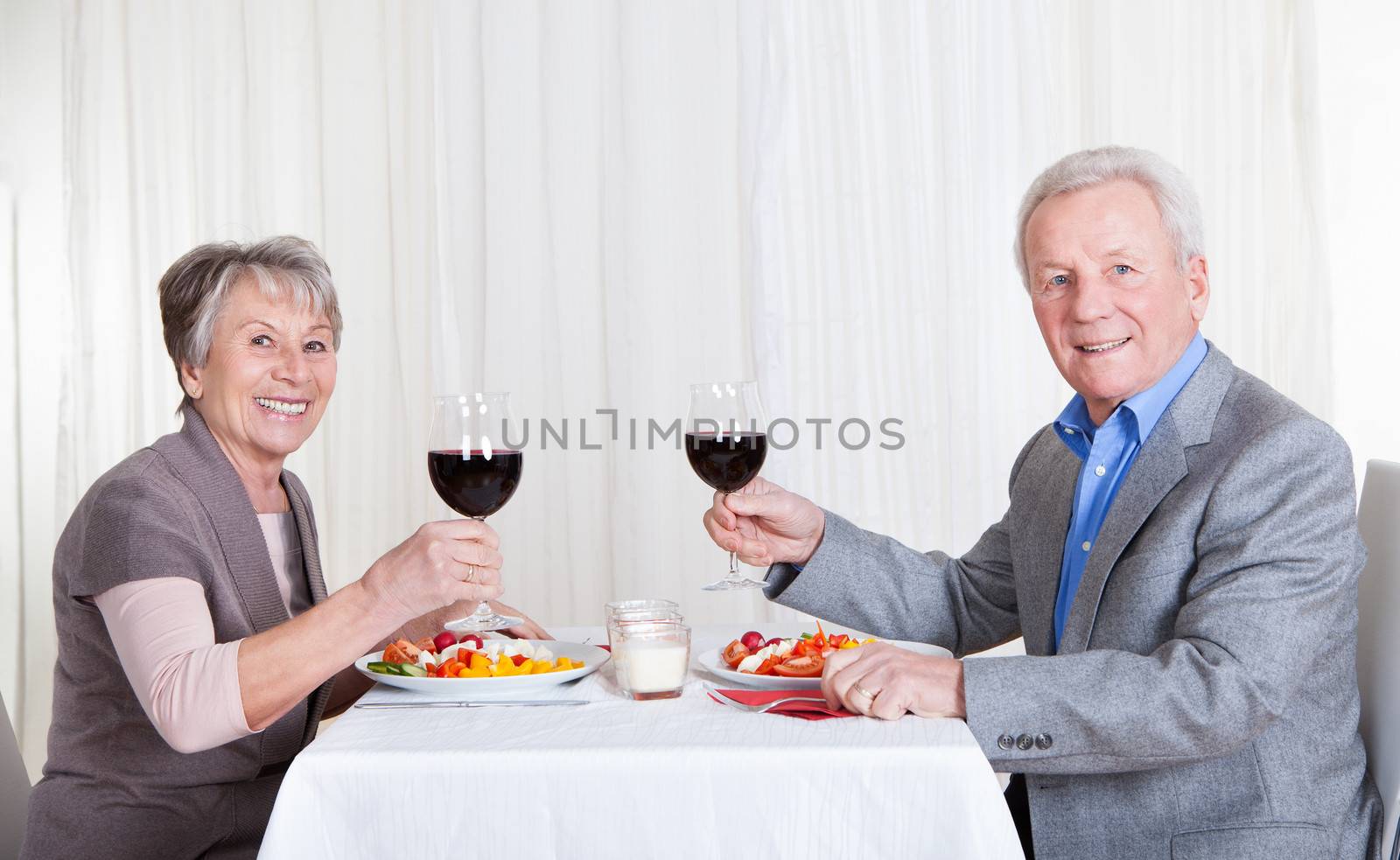 Portrait Of Senior Couple With Wine Glasses Sitting At A Restaurant