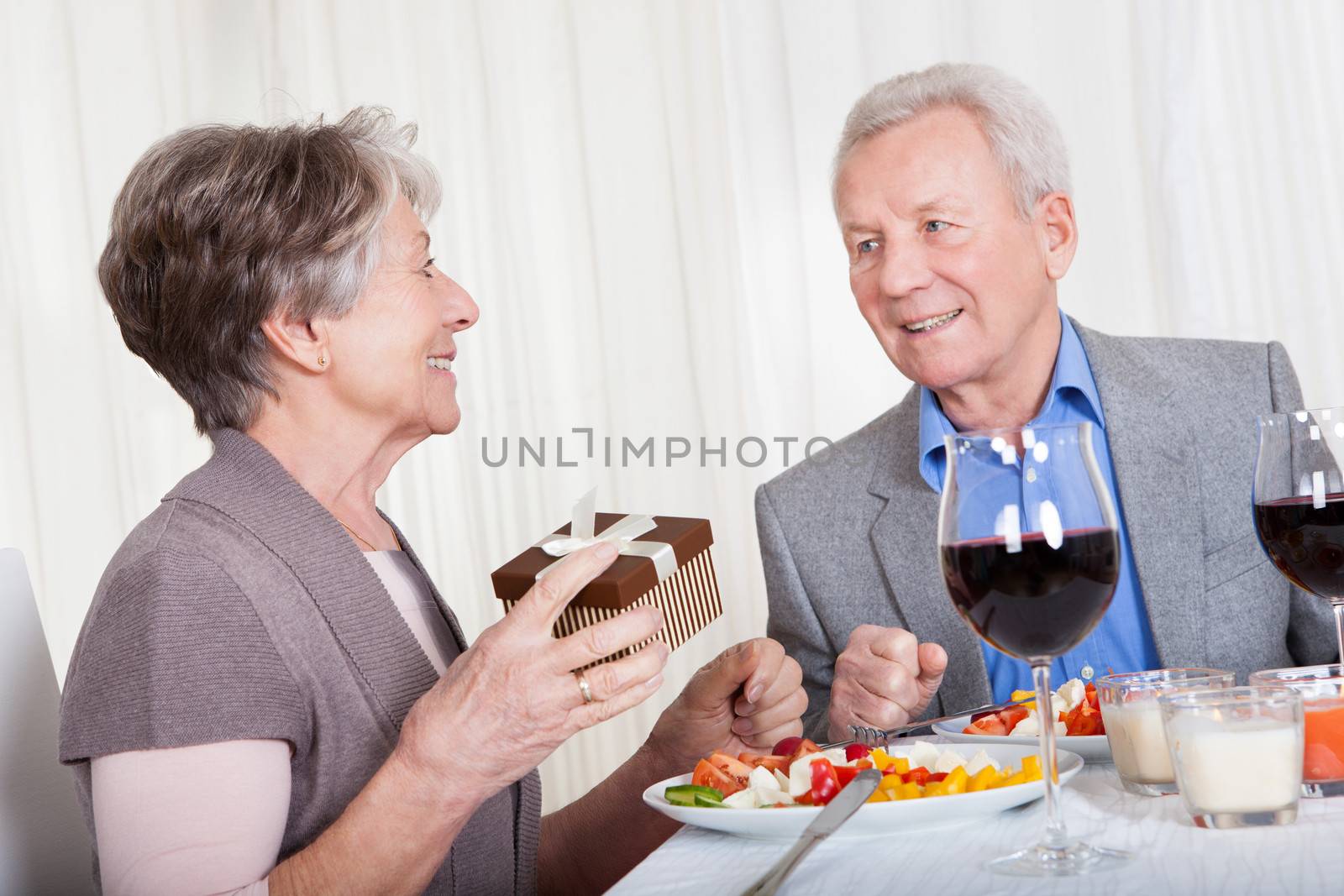 Senior Man Giving Gift To Senior Woman In Restaurant