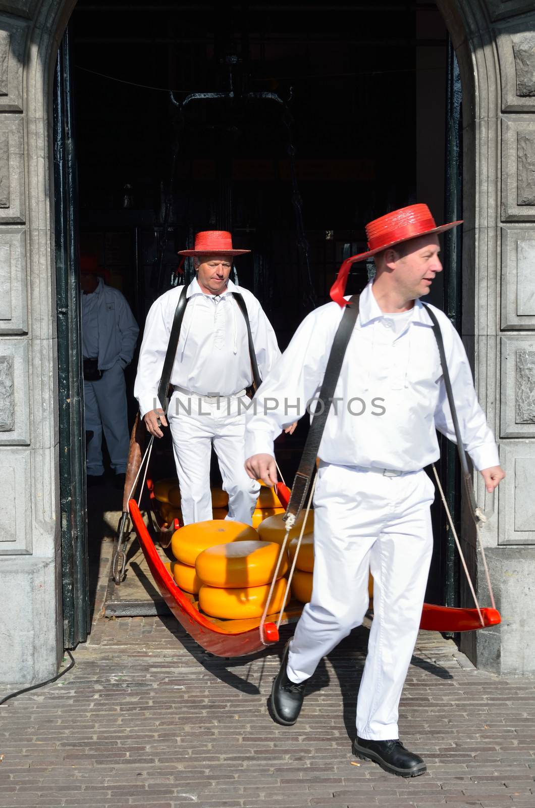 Alkmaar, the Netherlands – April 6, 2012: Two men carrying cheese on the famous cheese market in Alkmaar in the Netherlands.