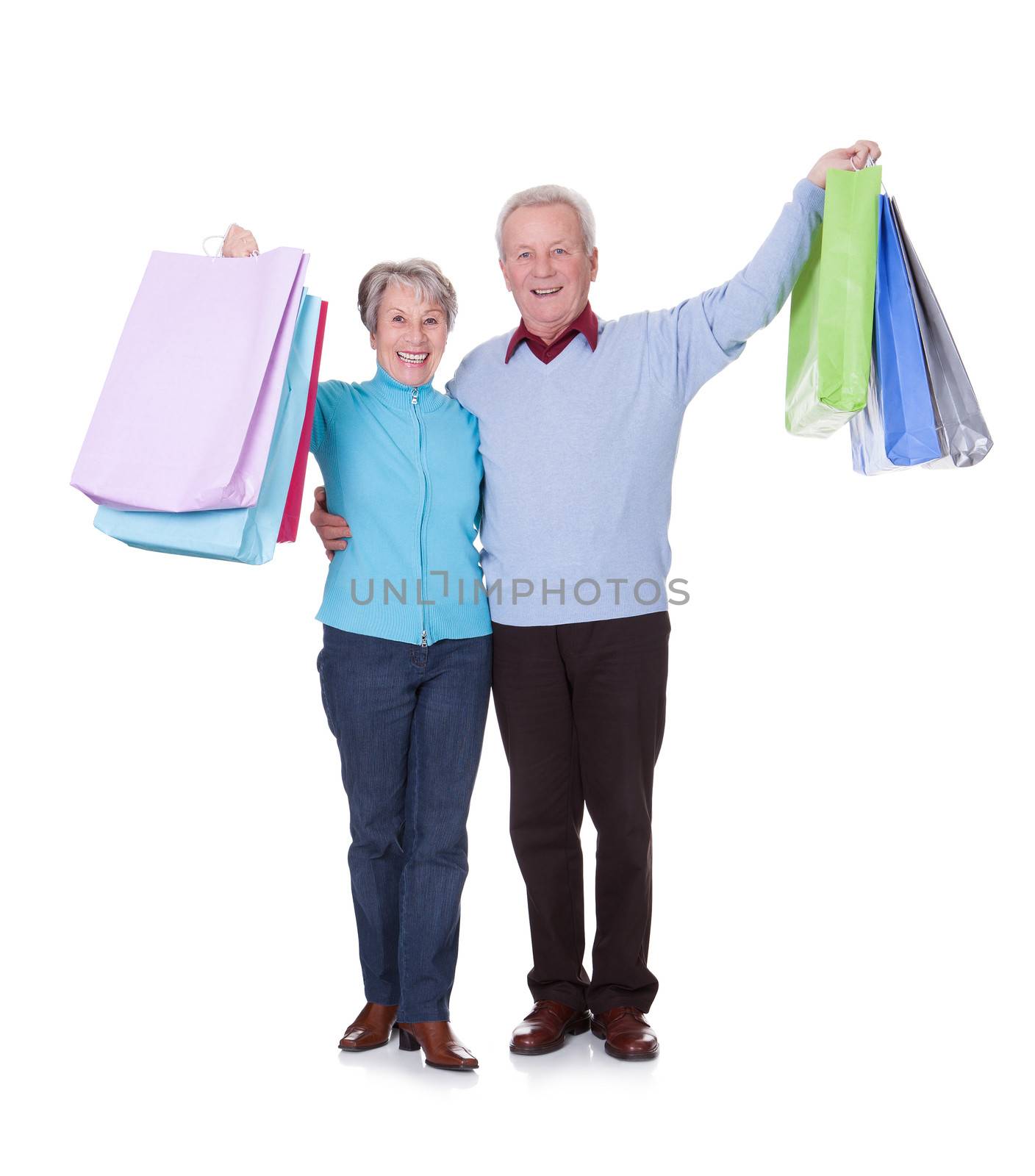 Portrait Of Happy Senior Couple Holding Shopping Bags