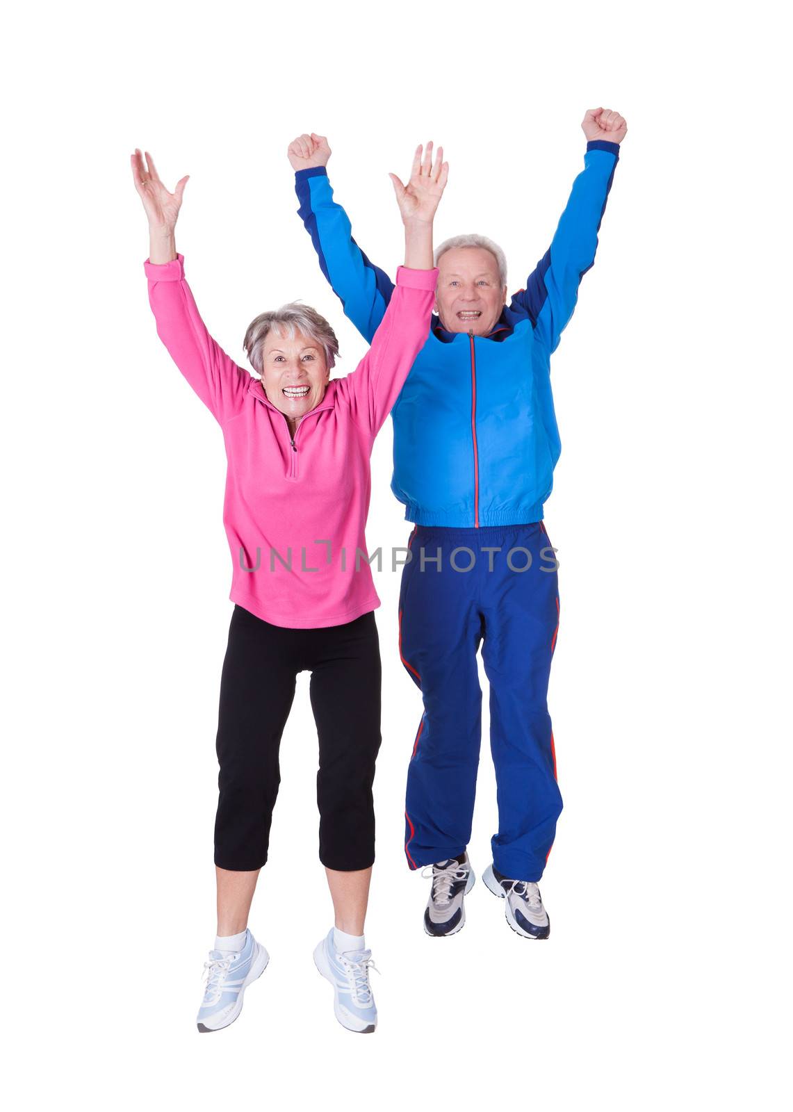 Portrait Of Senior Couple Jumping In Joy Over White Background