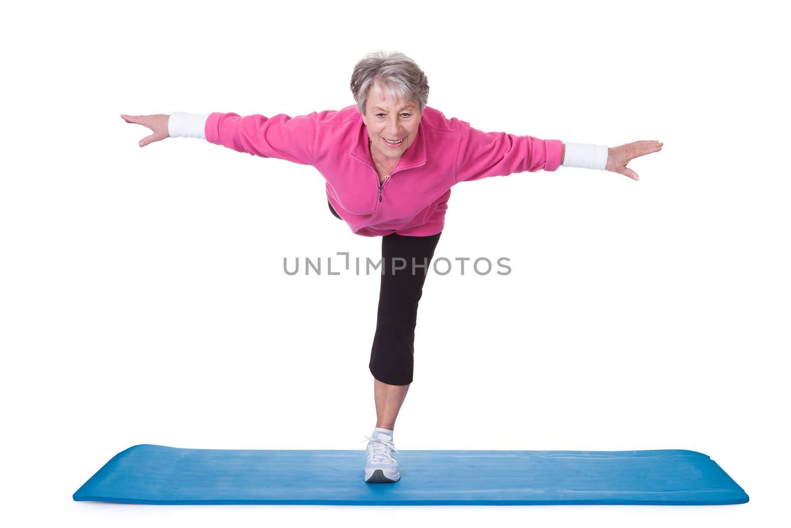 Senior Woman Standing On One Leg And Exercising Over White Background