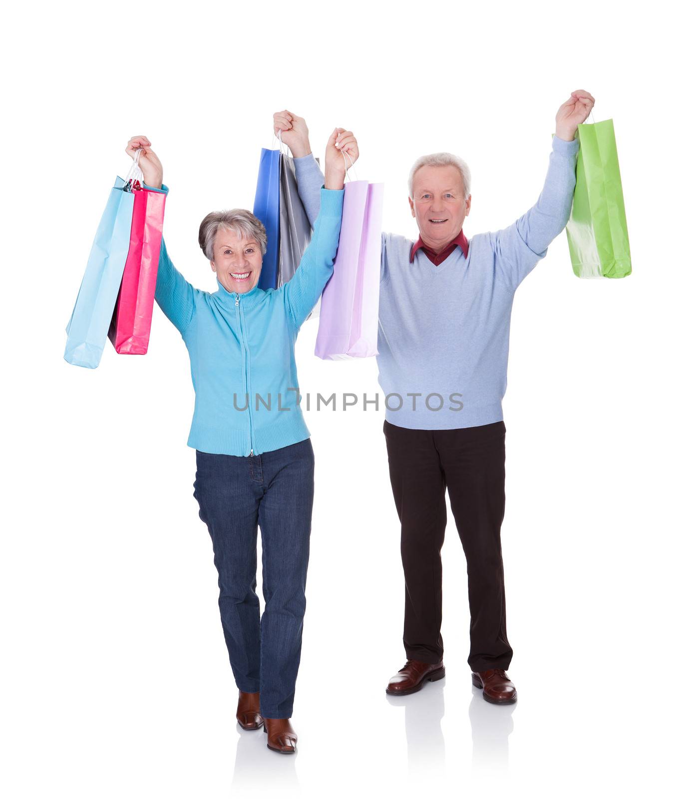 Portrait Of Happy Senior Couple Holding Shopping Bags