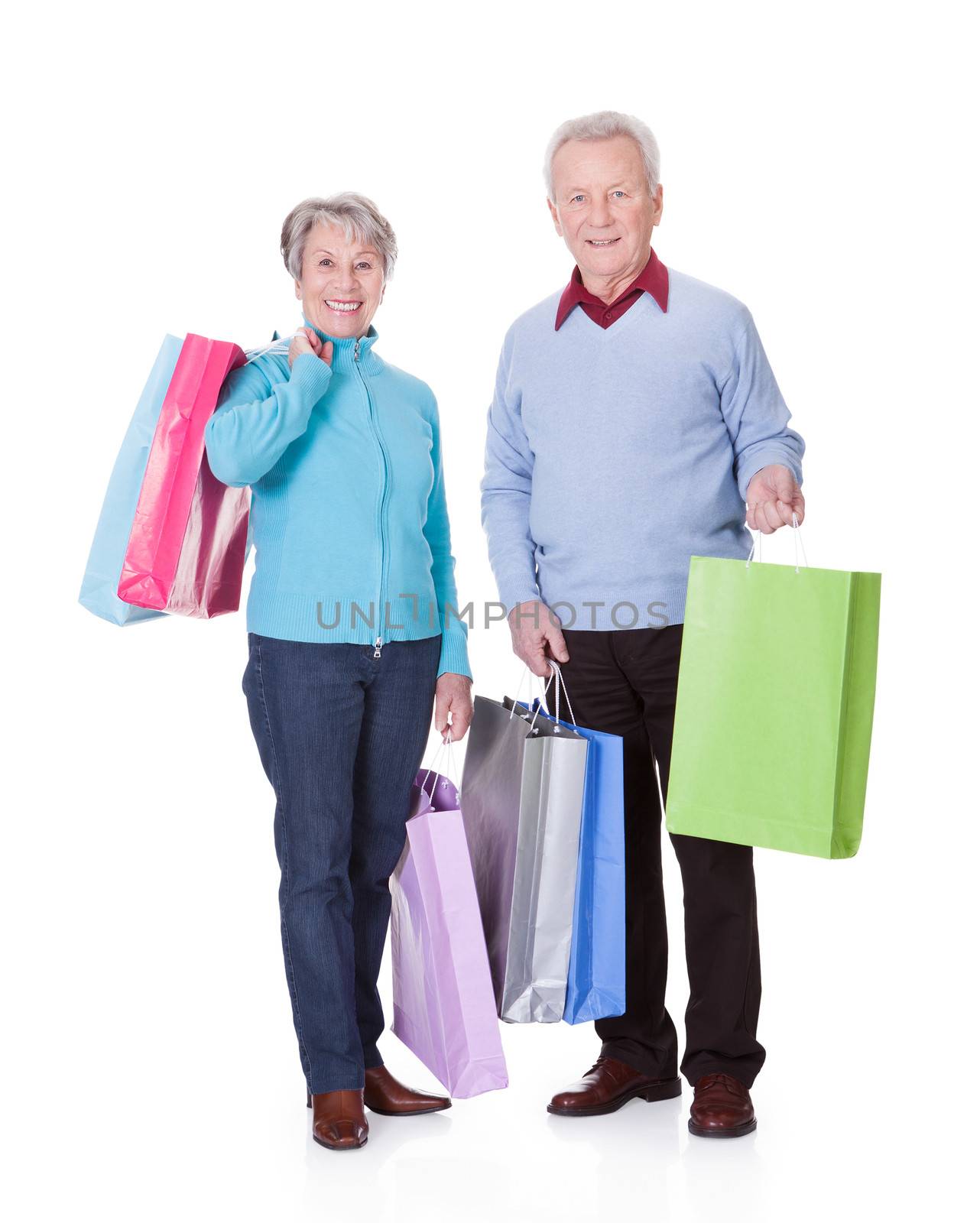 Portrait Of Happy Senior Couple Holding Shopping Bags