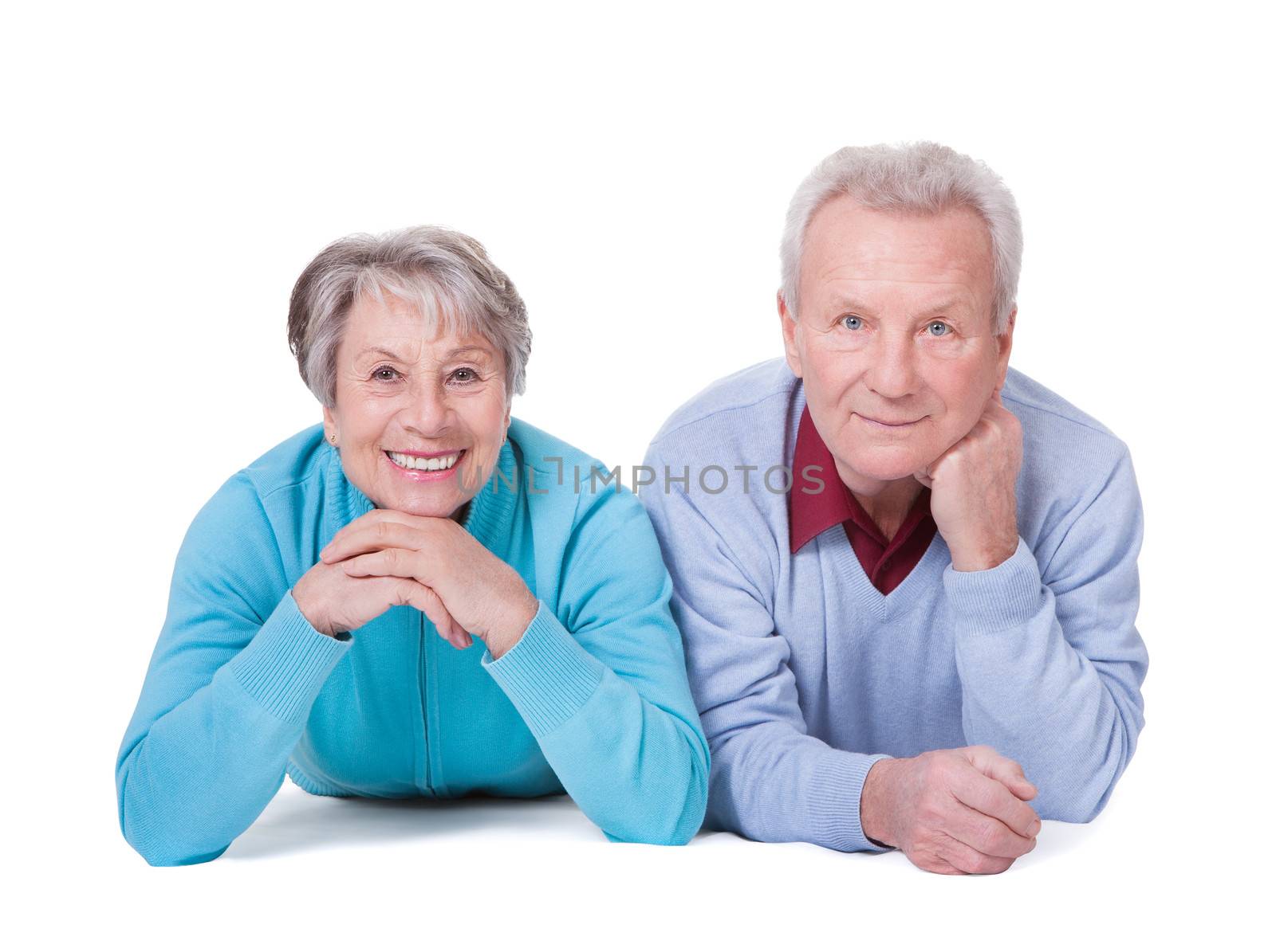Portrait Of Happy Senior Couple Lying Over White Background
