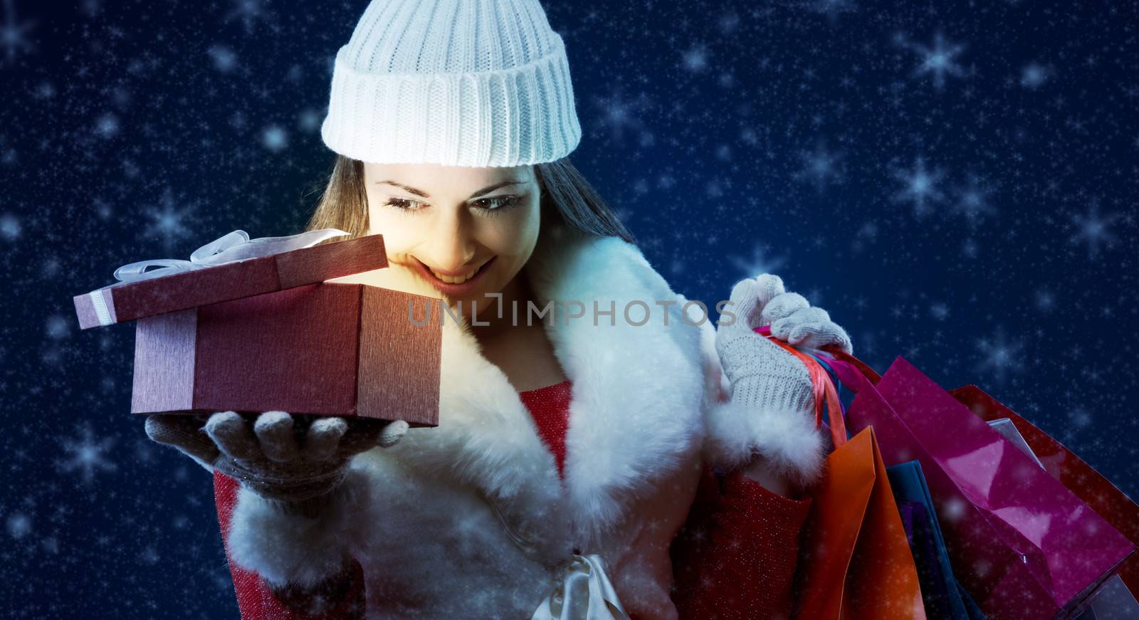 Happy young woman opening Christmas presents, copy space