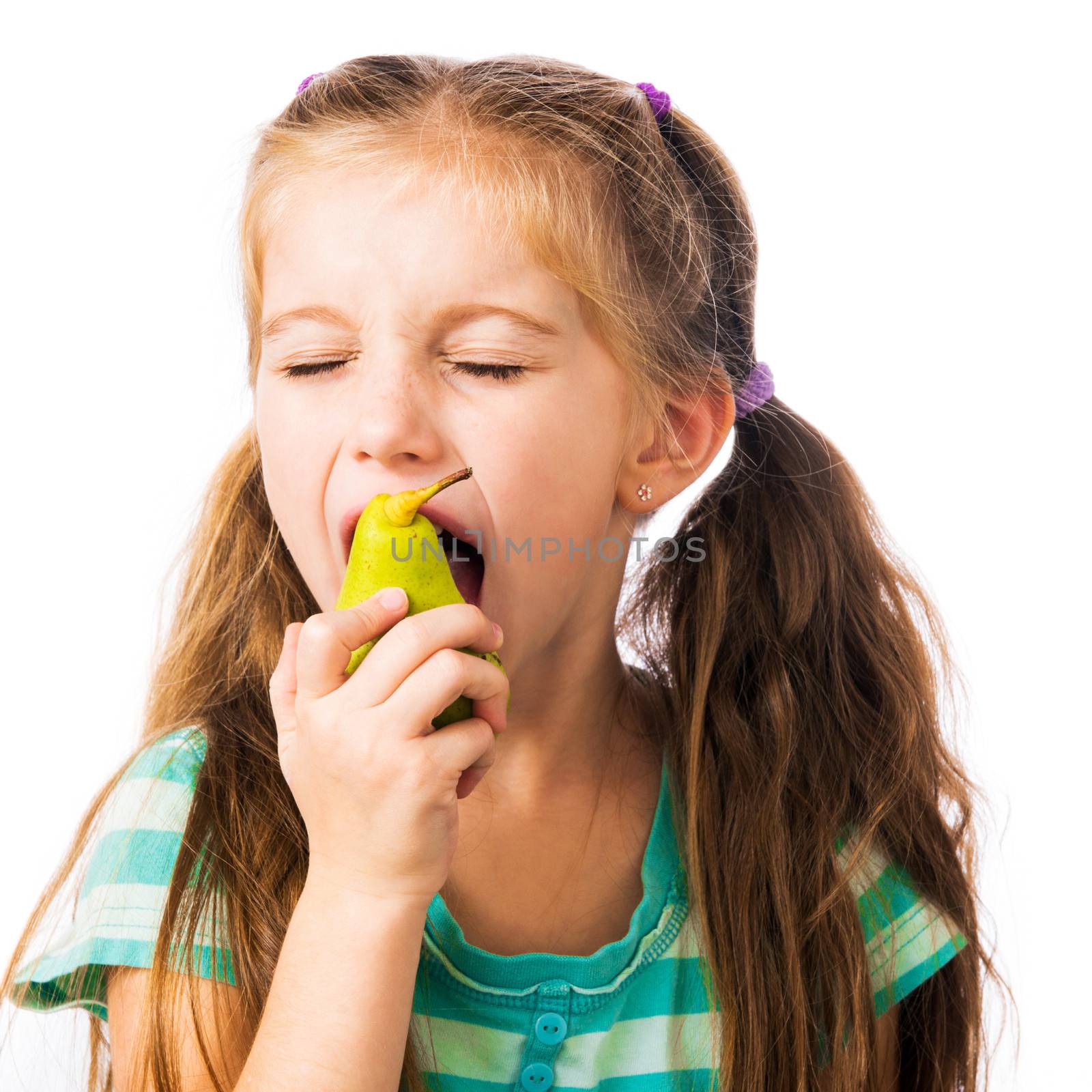 little girl biting pear on a white background