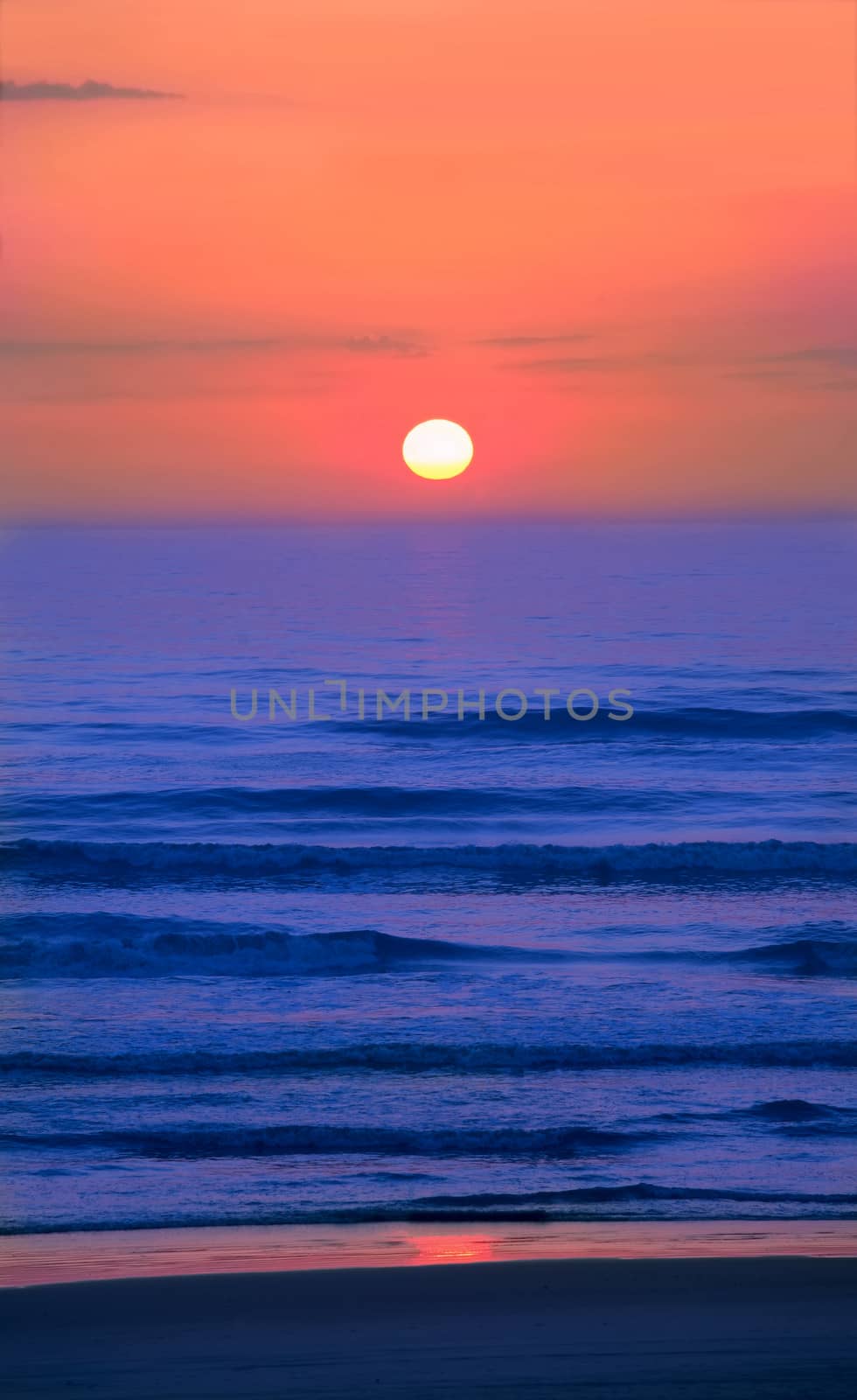 Beautiful, colorful sunset over the ocean shore with gentle waves