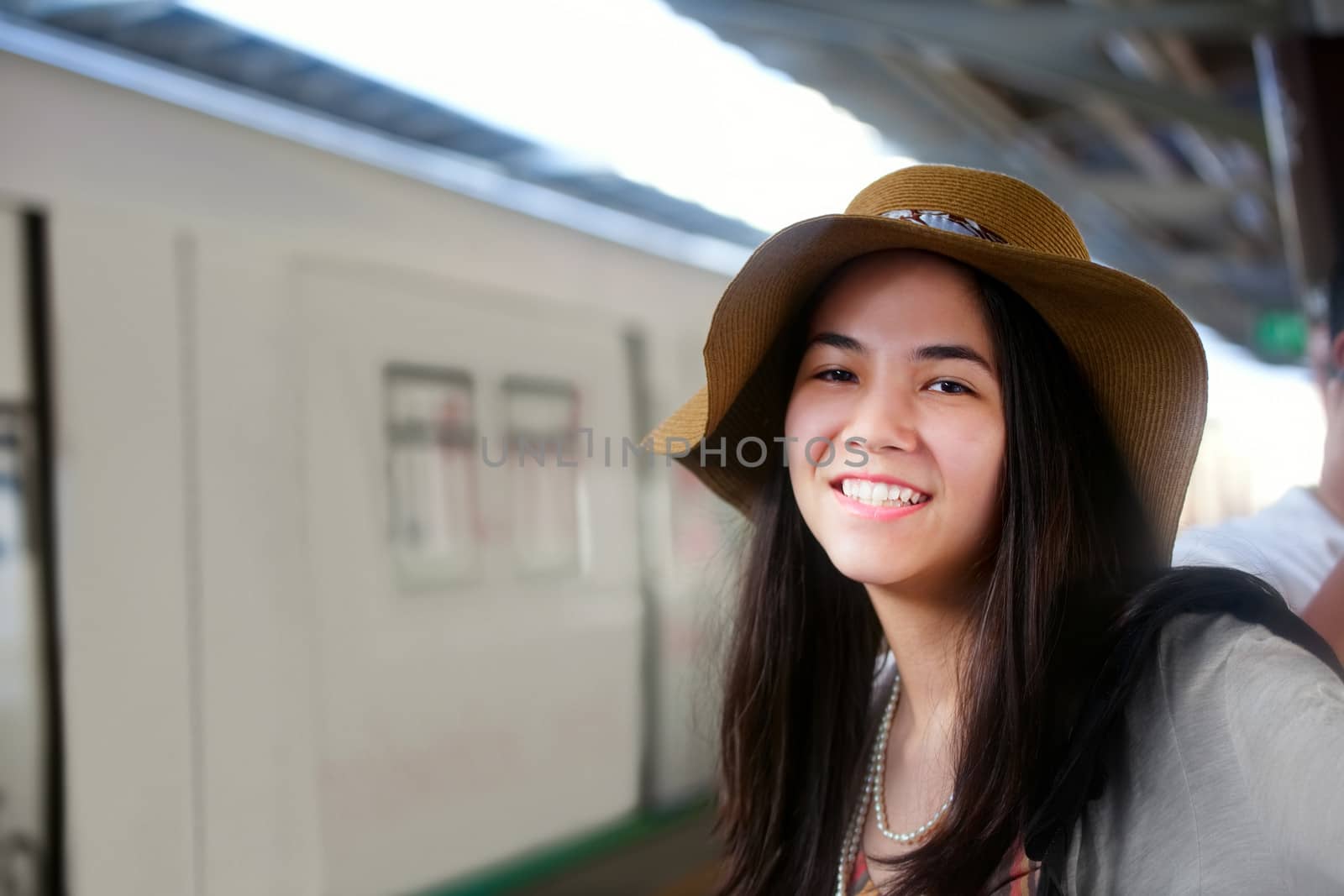 Smiling biracial teen traveler waiting for train at station in Thailand