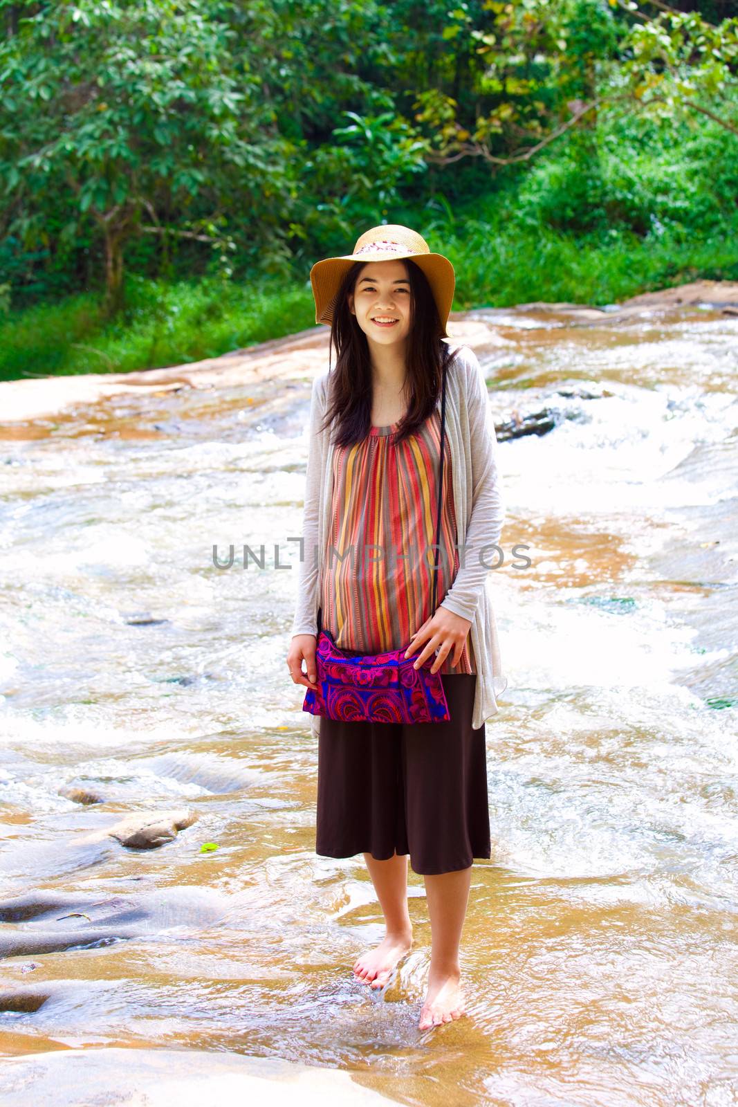 Biracial teen girl standing in shallow water, smiling