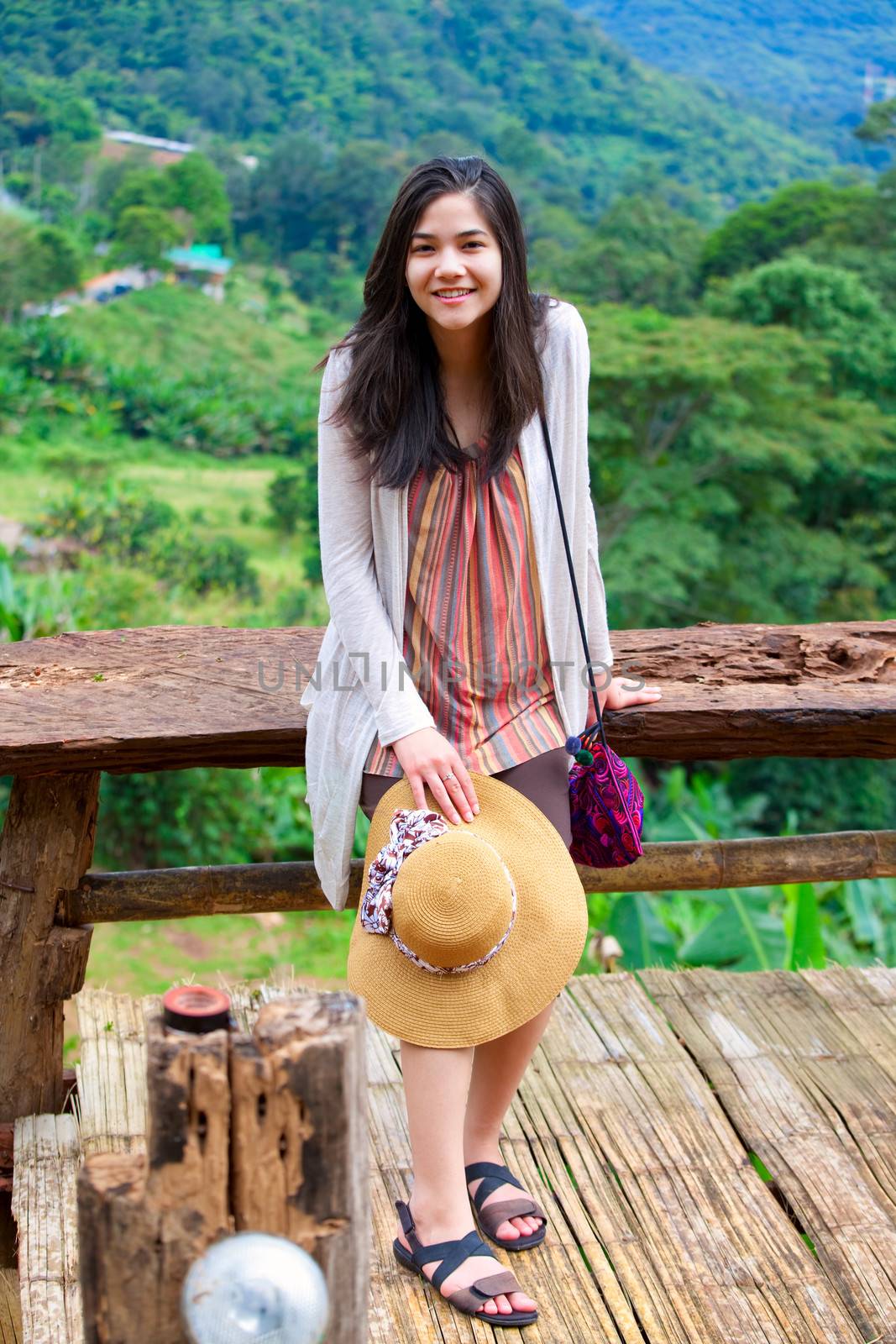 Biracial teen girl on decking , green mountainside of Thailand