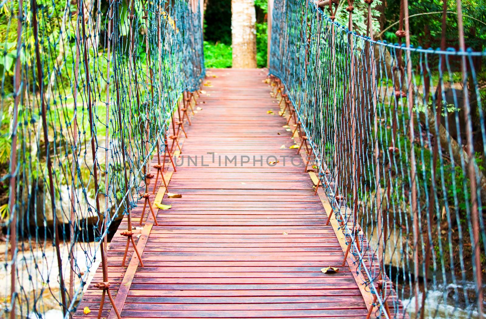 Wooden hanging suspension bridge in middle of woods