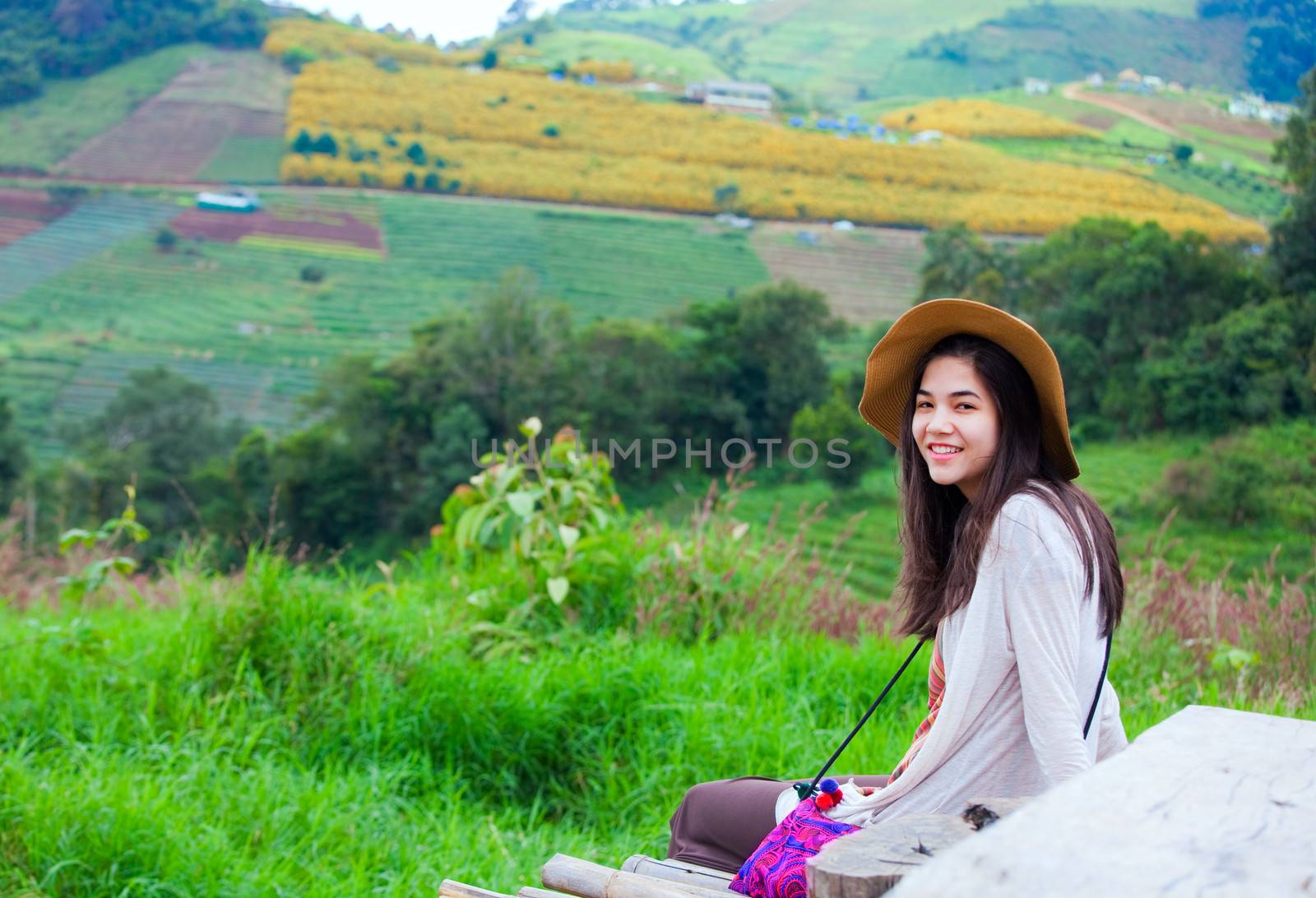 Biracial teen girl sitting on colorful hillside of Thailand