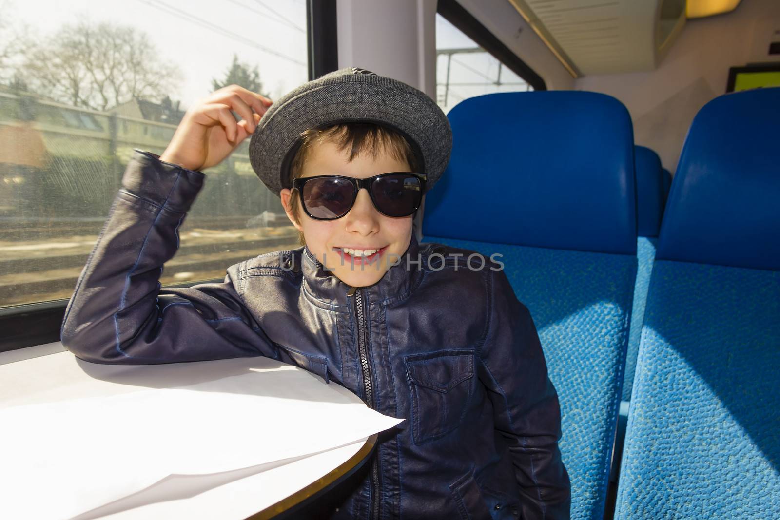 Handsome boy in sunglasses rides on a train by Tetyana