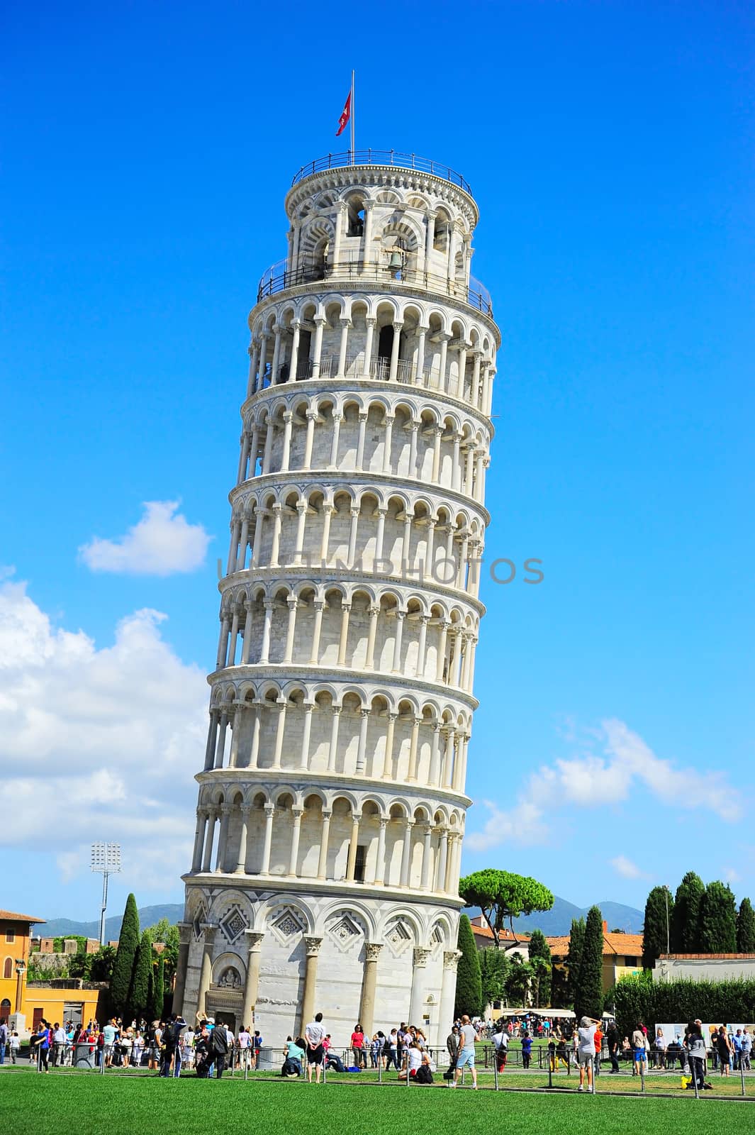 PISA, ITALY - SEPTEMBER 11, 2013: Tourists on Square of Miracles visiting Leaning Tower in Pisa, Italy. Leaning Tower of Pisa is campanile and is one of the most famous buildings in the world 