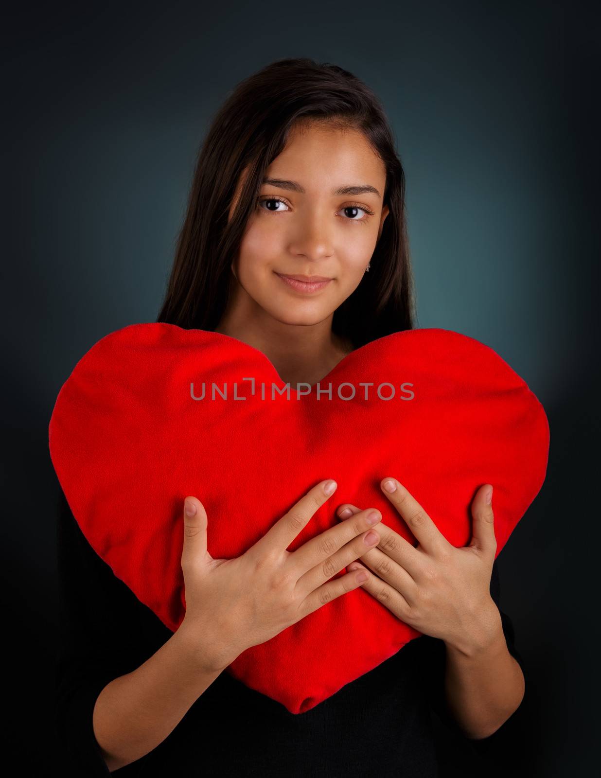 Beautiful girl holding a big plush heart-shaped pillow.